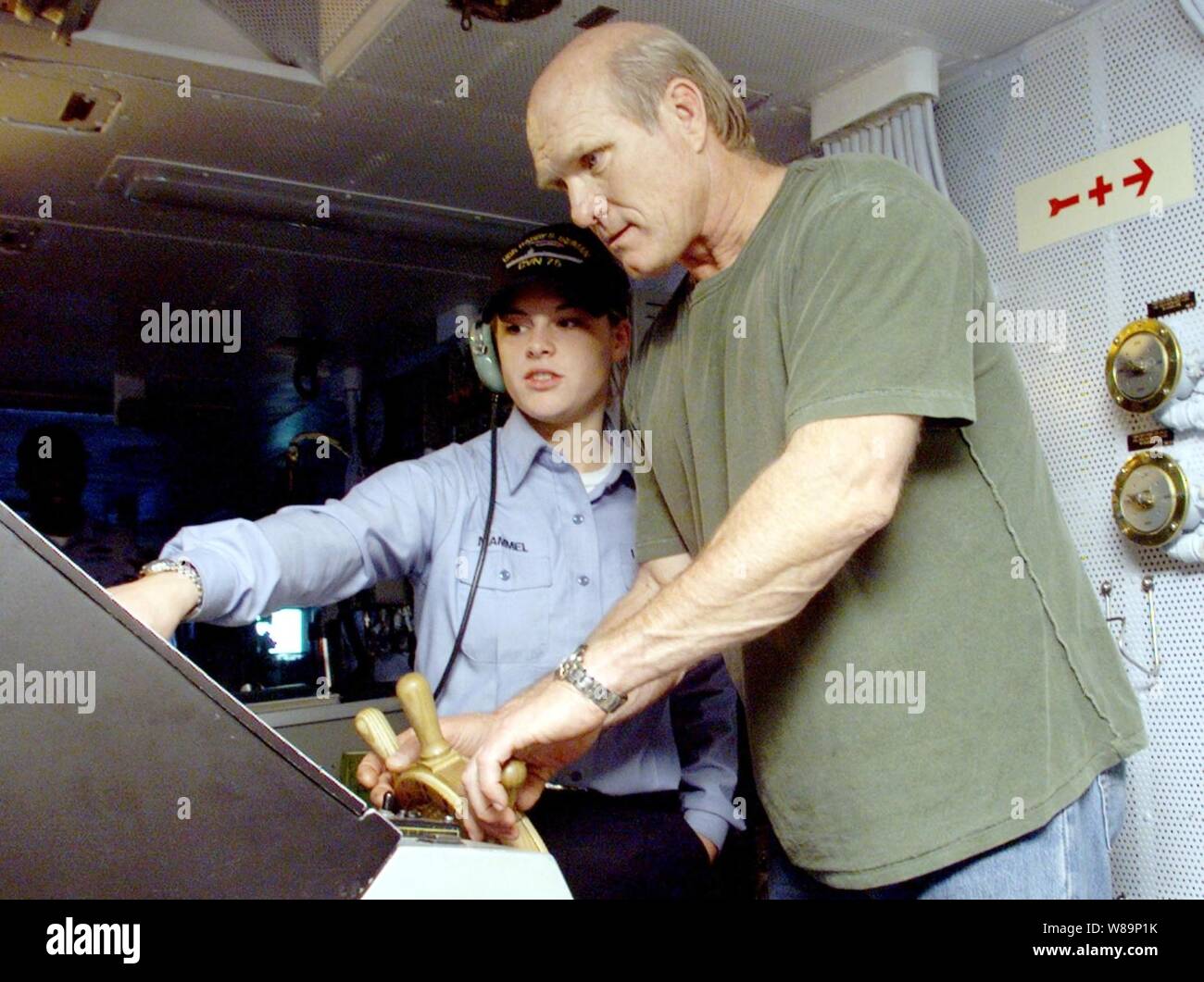 Fox Sports celebrity Terry Bradshaw (destra) cerca la sua mano a sterzare la USS Harry Truman (CVN-75) sotto l'occhio vigile del marinaio Blair C. Mammel su dicembre 14, 2000. Mammel, chi è un qualificato shipХs timoniere, Bradshaw ha dato alcune indicazioni dello sterzo sulla portaerei, che è quasi quattro campi da calcio a lungo. Bradshaw è a bordo degli aeromobili del vettore al nastro della National Football League Pre-Game mostrano di essere trasmesso sulla rete di Fox nel dicembre del XVI e del xvii. Il Truman Battle Group è operativo nel mar Mediterraneo su un programmato sei mesi di distribuzione. Mammel è da Billings, Mon Foto Stock