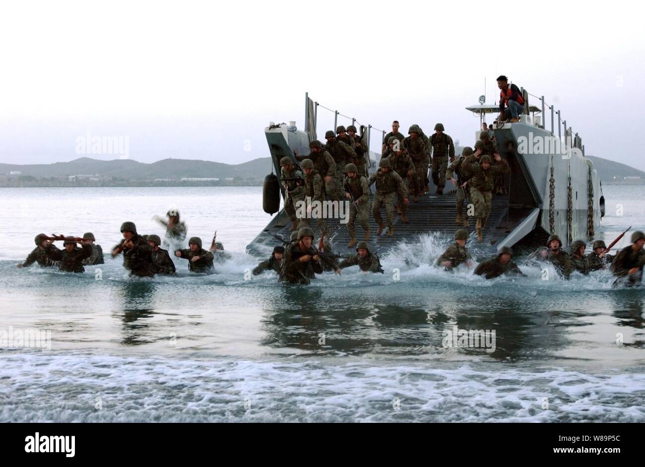 Stati Uniti Marines e marinai assegnato al 1 ° Flotta antiterrorismo del team di protezione, settimo plotone, saltare fuori della loro landing craft e immergersi nel surf durante un pre-alba assalto anfibio esercizio a Guantánamo Bay a Cuba, il 23 giugno 2004. Foto Stock