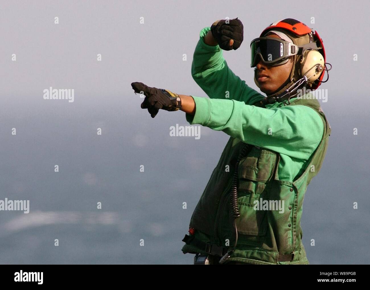 Navy Airman Chara Neal segnali pilota di una SH-60 Seahawk elicottero che vi sono il personale uscire dall'aeromobile sul ponte di volo della portaerei USS Harry Truman (CVN 75) come la nave opera nel Golfo Persico nel Febbraio 1, 2005. Il Truman Strike gruppo e Carrier aria Wing 3 sono in conduzione chiudere il supporto aereo, intelligence, sorveglianza e ricognizione missioni oltre l'Iraq. Neal è assegnato un elicottero Anti-Submarine Squadron 7 della Naval Air Station North Island, a San Diego, California Foto Stock