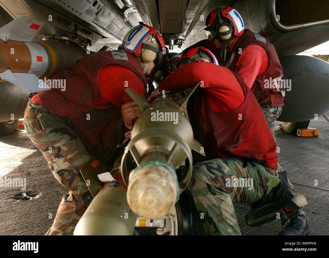 Aviazione Navy Ordnancemen lavorano insieme per montare laser bombe guidate al di sotto di un F-14B Tomcat durante il combattimento i preparativi per il ponte di volo della portaerei USS Harry Truman (CVN 75) il 1 febbraio 2005. Aeromobile da Carrier aria Wing 3 ha intrapreso la Truman stanno fornendo aria vicino sostegno e conduzione di intelligenza, missioni di sorveglianza e ricognizione durante le operazioni nel Golfo Persico. Foto Stock