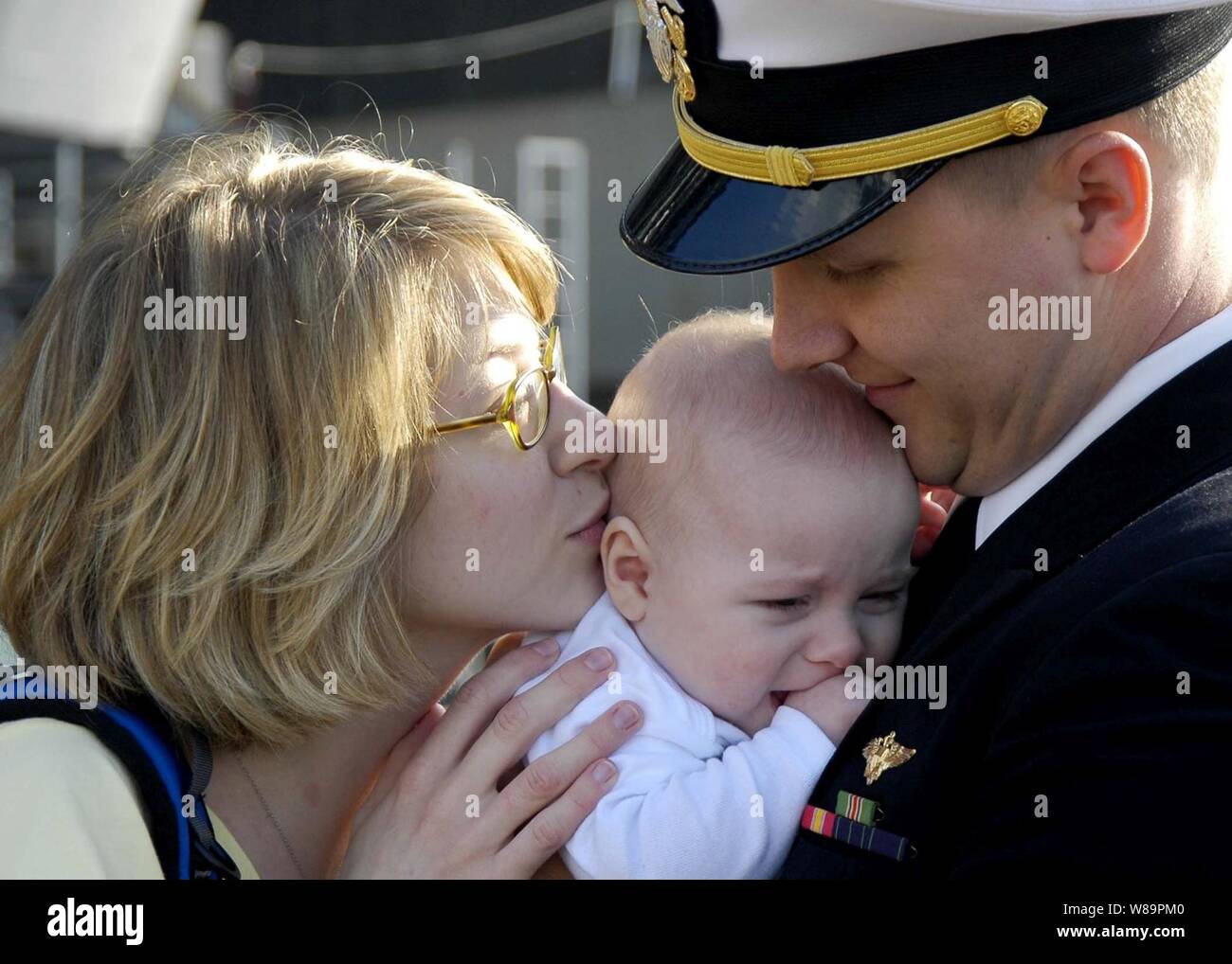 Un ufficiale della Marina dice ciao al suo bambino per la prima volta dopo il ritorno a casa di Naval Air Station North Island a San Diego, California, da una distribuzione a bordo della USS Abraham Lincoln (CVN 72) il 1 marzo 2005. La Nimitz-class portaerei Lincoln tirato in San Diego a scendere i marinai e Marines assegnati al vettore Air Wing 2 e quindi rendere il suo transito fino alla costa al suo homeport di Everett, Washington. Foto Stock