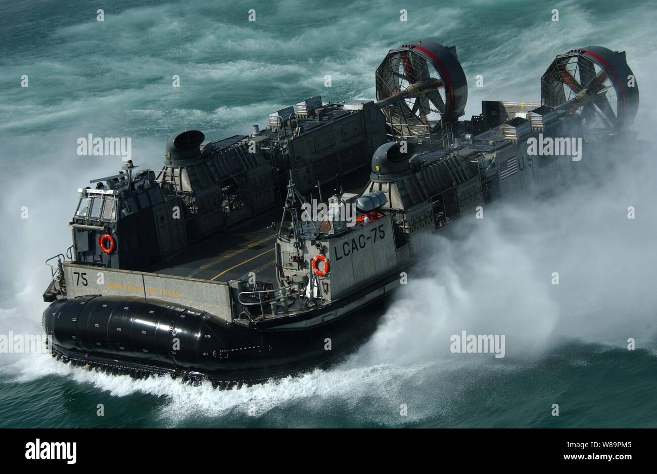 Un U.S. Navy Landing Craft Air Cushion, più comunemente noto come un LCAC, calci fino spray come teste per il Kuwait Base Navale dal dock anfibio sbarco nave USS harpers Ferry (LSD 49), il 5 marzo 2005. Harpers Ferry è parte di Expeditionary Strike gruppo 3 ed è attualmente distribuito al Golfo Persico a sostegno dell'Operazione Iraqi Freedom. Il LCAC è attaccato al mestiere di assalto unità 5 a Camp Pendleton, California, e viene distribuito a bordo della harpers Ferry. Foto Stock