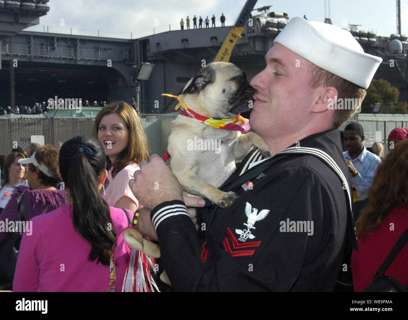 Una Marina petty officer è ha accolto con entusiasmo dal suo cane dopo il ritorno a casa di Naval Air Station North Island a San Diego, California, da una distribuzione a bordo della USS Abraham Lincoln (CVN 72) il 1 marzo 2005. La Nimitz-class portaerei Lincoln tirato in San Diego a scendere i marinai e Marines assegnati al vettore Air Wing 2 e quindi rendere il suo transito fino alla costa al suo homeport di Everett, Washington. Foto Stock