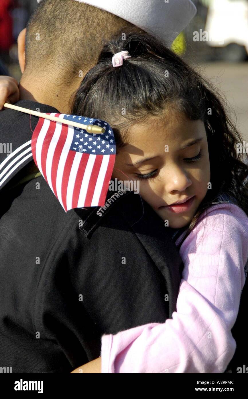 Un marinaio è abbracciato da sua figlia come egli ritorna alla casa del Naval Air Station North Island a San Diego, California, da una distribuzione a bordo della USS Abraham Lincoln (CVN 72) il 1 marzo 2005. La Nimitz-class portaerei Lincoln tirato in San Diego a scendere i marinai e Marines assegnati al vettore Air Wing 2 e quindi rendere il suo transito fino alla costa al suo homeport di Everett, Washington. Foto Stock