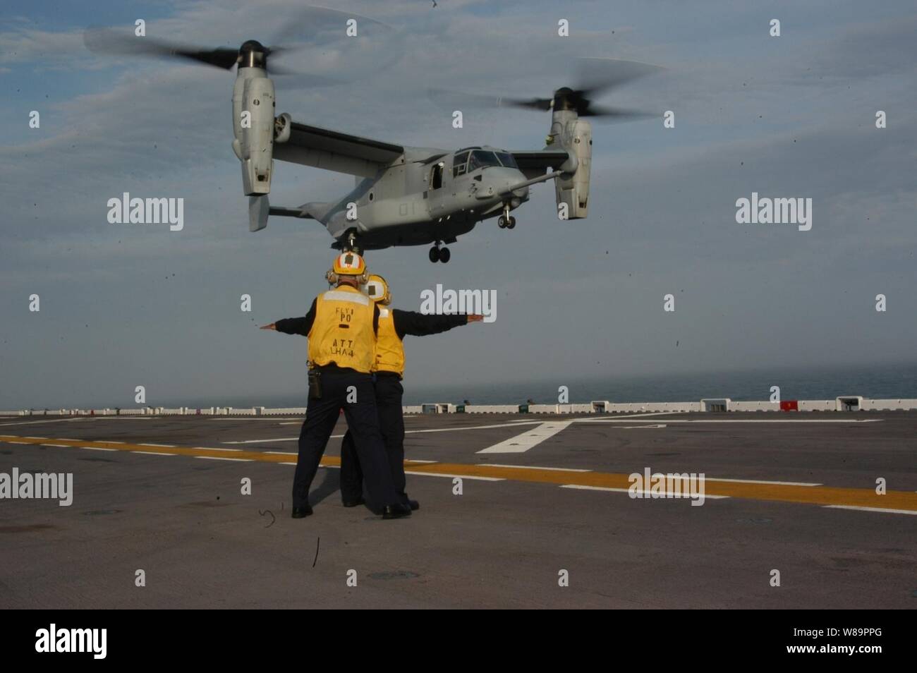 Ponte di volo segnale marinai i piloti di U.S. Marine Corps MV-22 Osprey come viene in per un atterraggio sulla USS Nassau (LHA 4) mentre è in corso nell'Oceano Atlantico il 23 marzo 2005. Il Falco pescatore è un decollo ed atterraggio verticali tiltrotor aeromobili progettati per combattere, combattere il supporto e le operazioni speciali missioni in tutto il mondo. Il ponte di volo equipaggio di Nassau ha lavorato con la Osprey per la prima volta durante un giro familiarizzazione in mare. La Osprey è attaccato al Tilt-Rotor Prova di funzionamento Squadron 22 dalla Marine Corps Air Station New River, N.C. Foto Stock