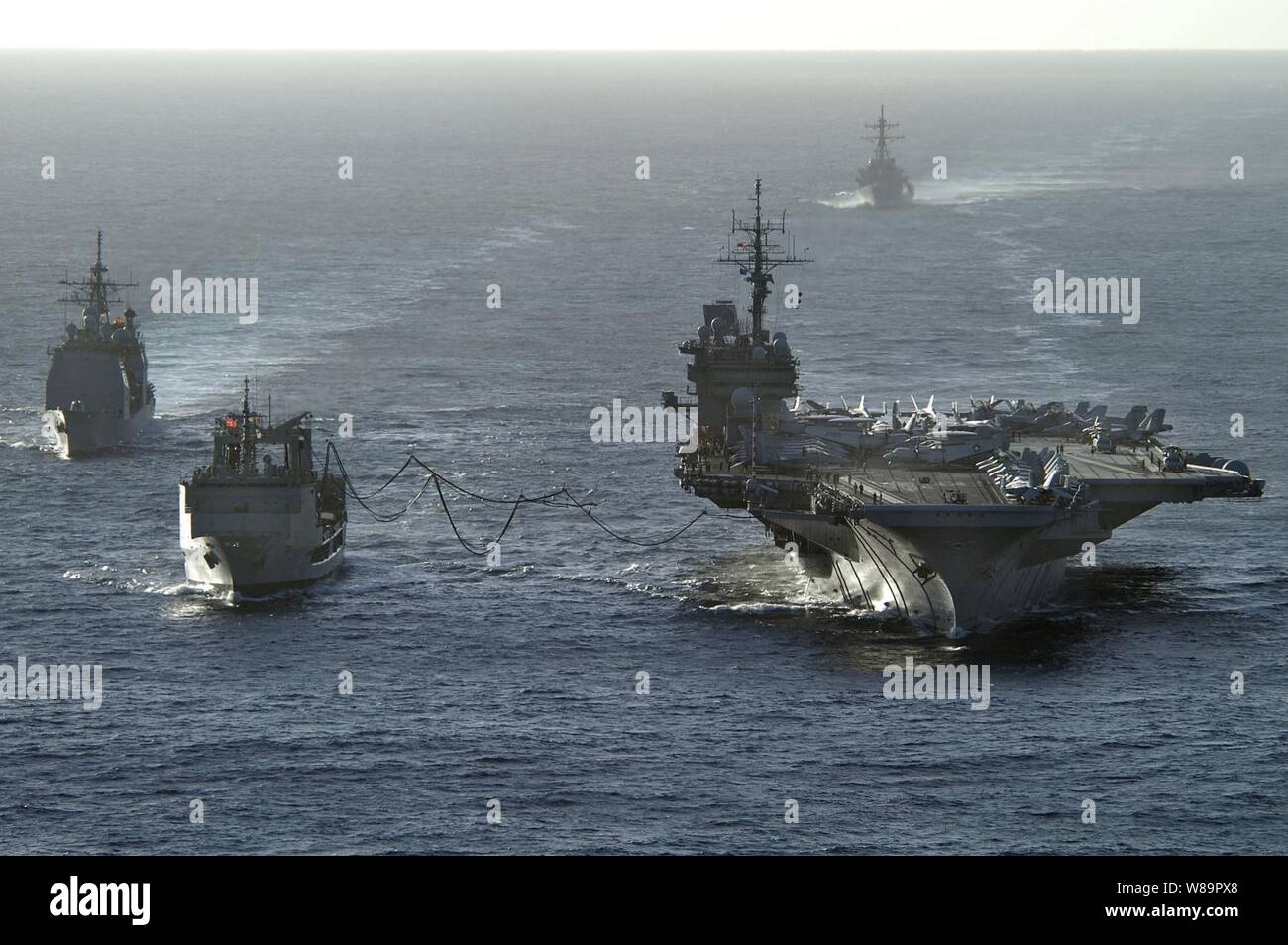 La portaerei USS Kitty Hawk (CV 63) riceve carburante durante un rifornimento in mare dalla Royal Australian Navy oliatore ausiliario nave rifornimento HMAS successo (AOR 304) come Stati Uniti Navy missile cruiser USS Cowpens (CG 63) vapori a fianco e missile destroyer USS John Paul Jones (DDG 53) percorsi dietro, il 14 giugno 2005. Le navi operanti nel Mare di corallo, al largo della costa australiana della regione del Queensland, come parte dell'esercizio talismano Saber 2005. Talismano Saber è un combinato di Stati Uniti-Australia sul posto di comando e la formazione sul campo esercizio, dimostrazione di Stati Uniti e Australia Foto Stock