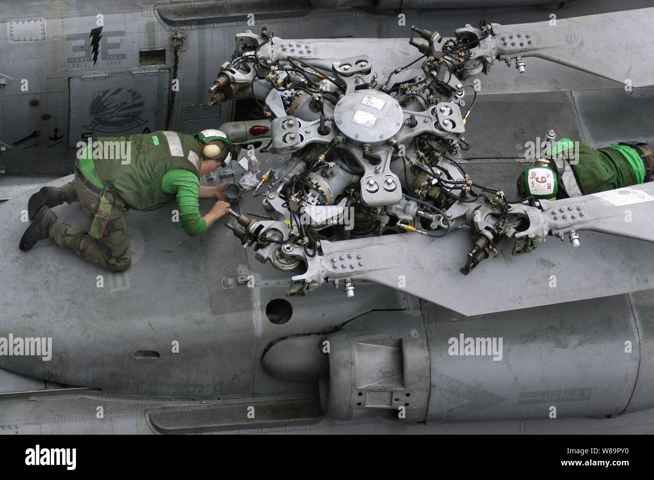Velisti assegnati all'elicottero Anti-Submarine Squadron 14 eseguire attività di routine di controllo di corrosione di manutenzione su un SH-60F Seahawk elicottero sul ponte di volo della portaerei USS Kitty Hawk (CV 63) il 20 giugno 2005. Il Kitty Hawk è operativo in mare di corallo al largo della costa australiana della regione del Queensland come parte di esercizio talismano Saber 2005. Talismano Saber è un combinato di Stati Uniti-Australia sul posto di comando e la formazione sul campo esercizio, dimostrando la U.S. e Australian impegno di alleanza militare e della sicurezza regionale. Foto Stock