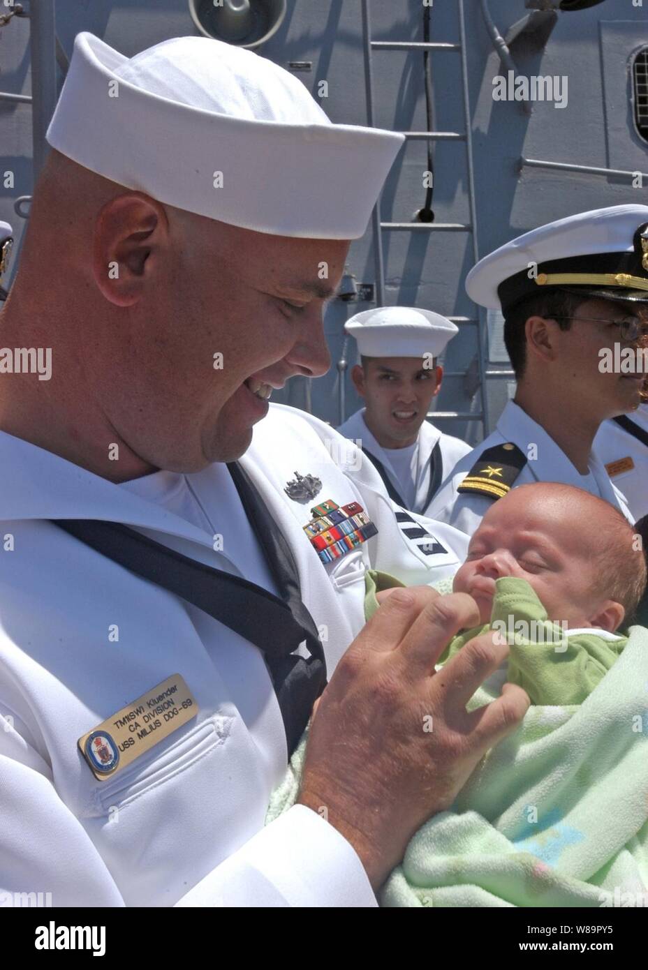 Petty Officer di prima classe Kluender Keith sorrisi come tiene il suo figlio neonato Cameron per la prima volta alla stazione navale di San Diego, California, dopo il ritorno da sei mesi di distribuzione a bordo della USS Milius (DDG 69) il 6 giugno 2005. Kluender è un Torpedoman's Mate a bordo del Arleigh Burke class destroyer. Foto Stock