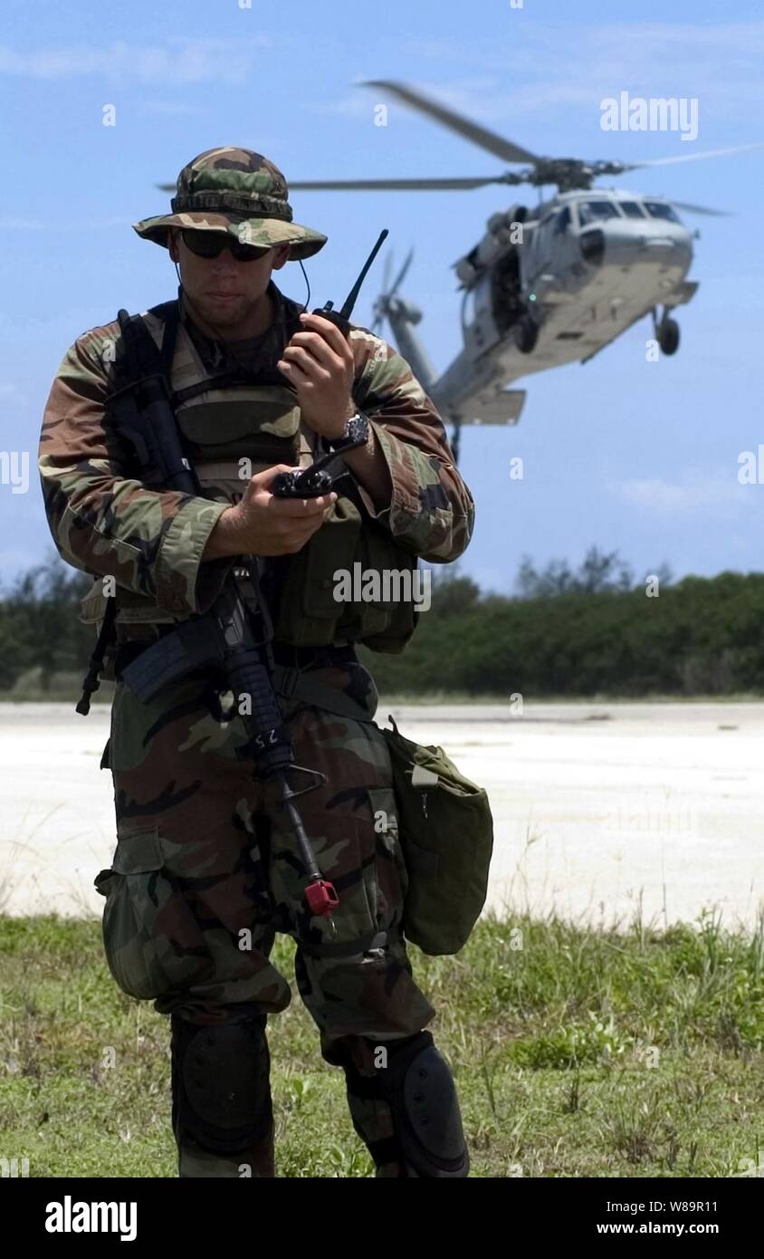 Navy Petty Officer 2a classe Jackson J. Stasny ascolta una chiamata sulla sua radio come un MH-60S elicottero si prepara a terra durante un esercizio presso la base navale di Guam, Santa Rita, Guam, il 30 giugno 2005. Stasny è con la Mobile Security Squadron 7 distacco 73, che è in corso la sua pre-esercizi di certificazione prima di essere ufficialmente esaminate per determinare se può essere certificato per l'installazione. Foto Stock