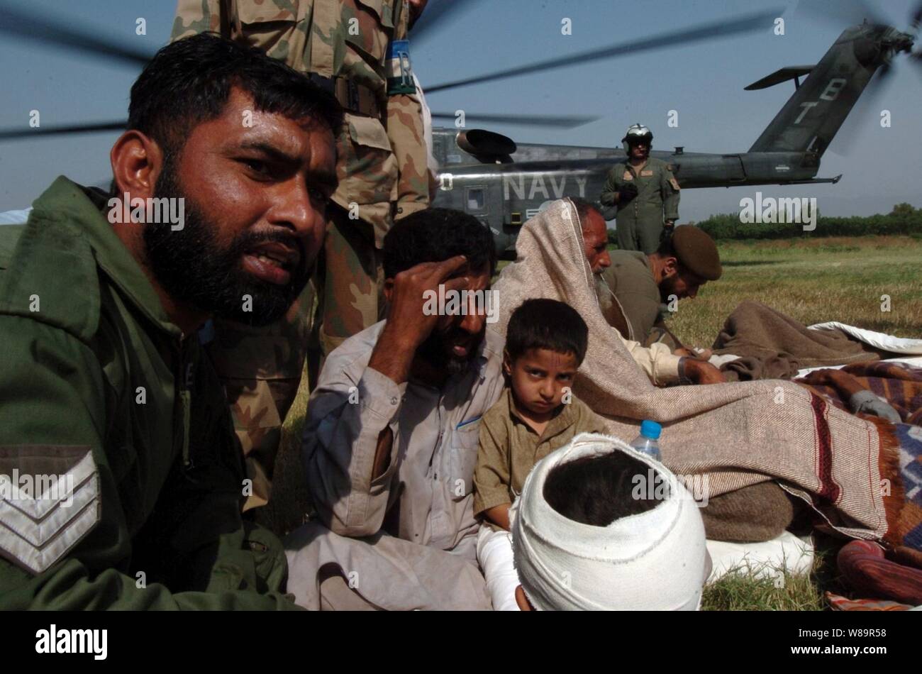 Un soldato pakistano comfort civili dopo che essi sono stati trasportati a bordo di una U.S. Navy MH-53 mare Dragon elicottero per trattamento medico in Chaklala, Pakistan, dal 14 ottobre, 2005. La Marina Militare Elicottero equipaggio consegnati di forniture di soccorso a Muzafarabad, Pakistan, poi trasferito in aereo i feriti. Il Dipartimento della Difesa sta sostenendo che il Dipartimento di Stato dai soccorsi in caso di disastri delle forniture e dei servizi a seguito del forte terremoto che ha colpito il Pakistan e parti dell India e l'Afghanistan. Il drago di mare e il suo equipaggio sono attaccati alla miniera di elicottero contromisura Squadron 15 della Naval Air Station N Foto Stock