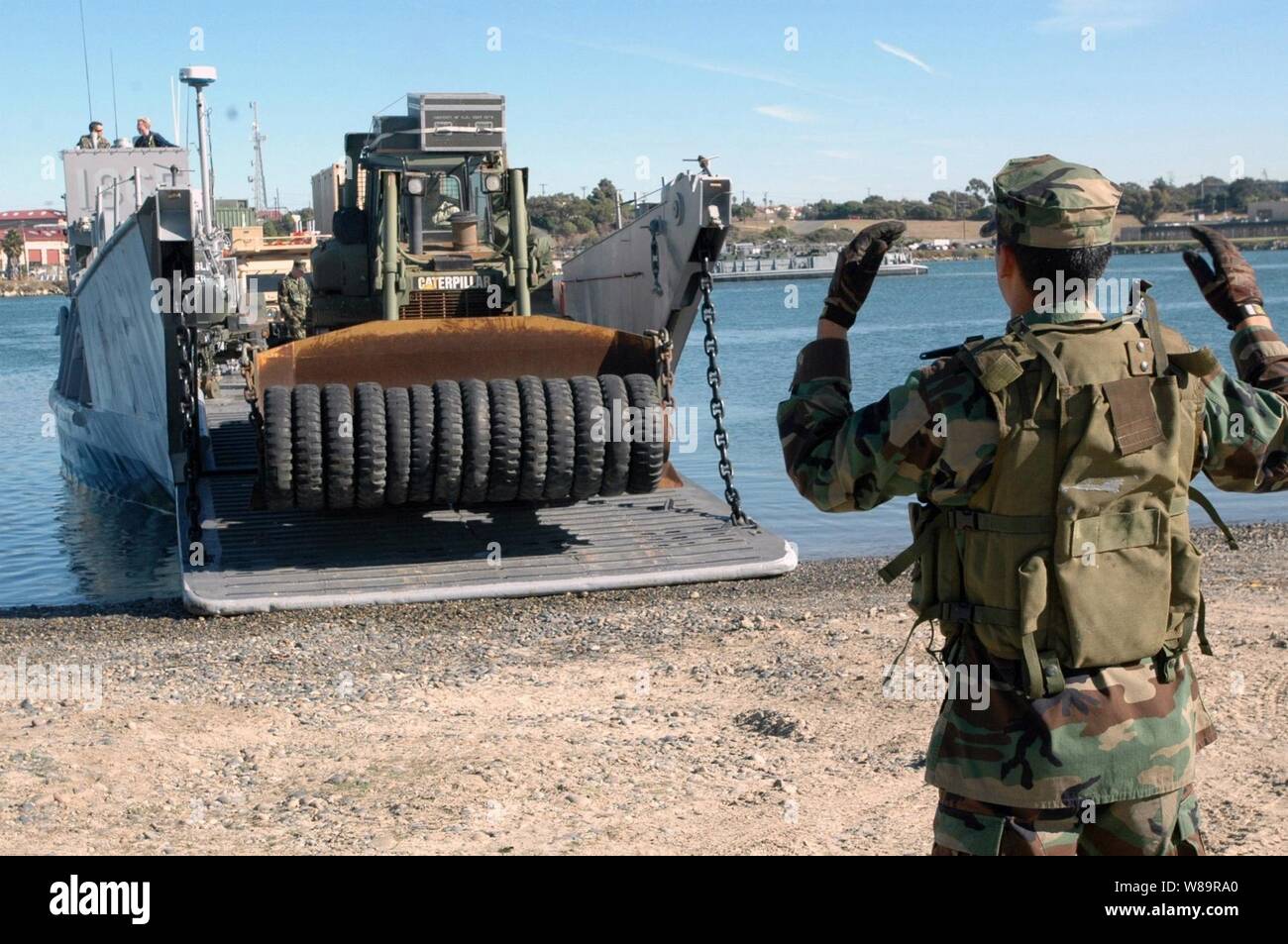 Petty Officer di terza classe Guadelupe Rivera dirige il driver di U.S. Bulldozer marino off di una landing craft al Del Mar bacino in barca a Camp Pendleton, California, il 5 dicembre, 2005. Il Landing Craft è il trasporto di marines della xi Marine Expeditionary Unit e le loro attrezzature da assalto anfibio nave USS Peleliu (LHA 5) a Camp Pendleton. Peleliu è in corso al largo della costa della California del Sud per esercitazioni navali in preparazione per la sua prossima distribuzione. Foto Stock