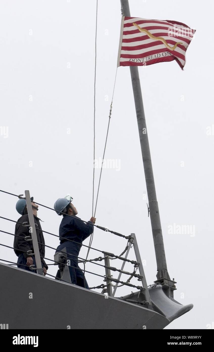 I marinai sul mare e i dettagli di ancoraggio abbassare il martinetto della marina come il missile destroyer USS Curtis Wilbur (DDG 54) riceve in modo da Yokosuka, Giappone, del 19 aprile 2006. La Marina Militare Jack è stato battenti in tutti gli Stati Uniti Navi della Marina militare dal Settembre 11, 2001, in onore di coloro che sono morti in quel giorno. Foto Stock