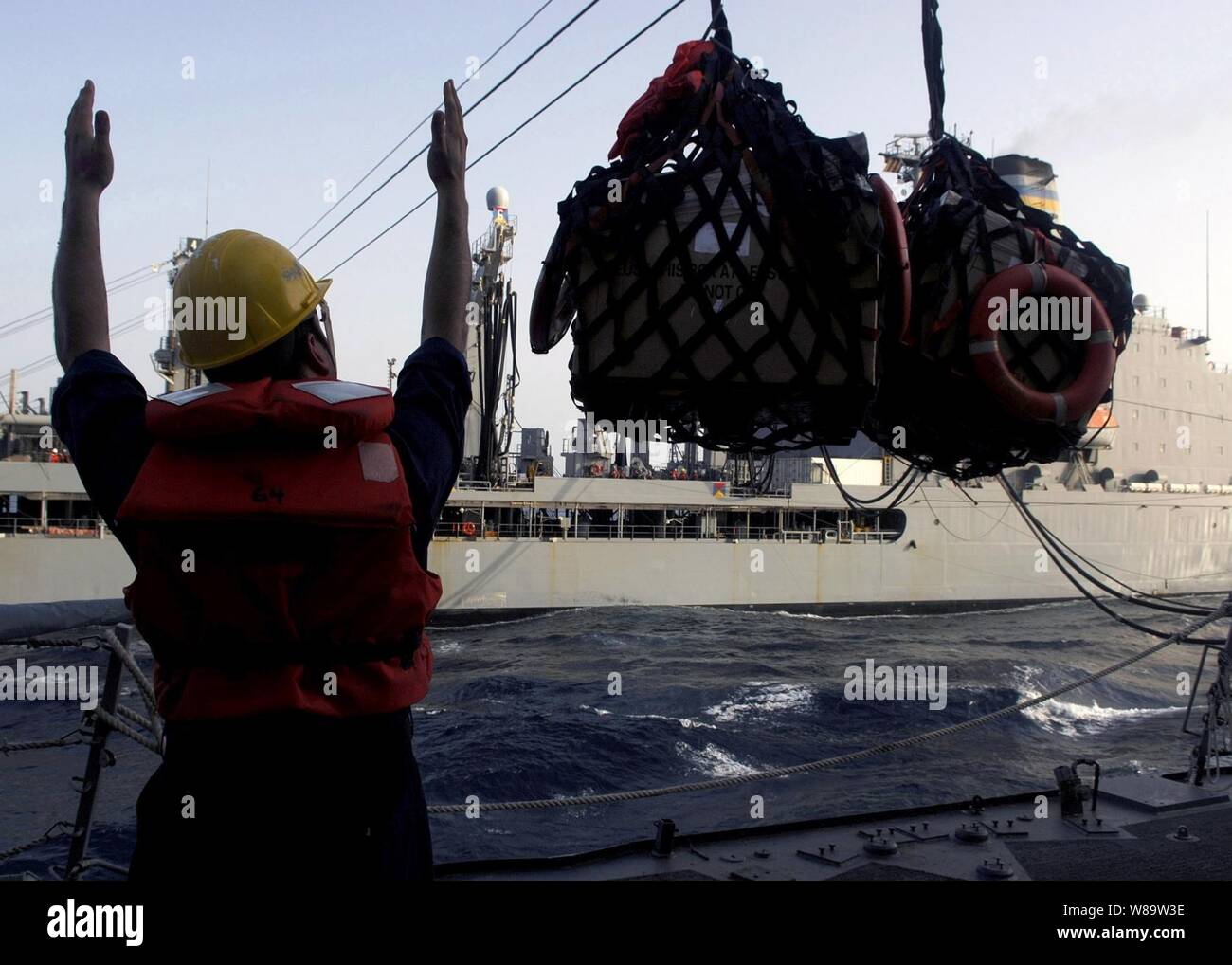 Un U.S. Navy marinaio a bordo guidato-missile destroyer Arleigh Burke (DDG 51) segnali che le forniture sono oltre il ponte della stazione ricevente durante un rifornimento in mare con la forza militare di comando Sealift flotta oliatore di rifornimento USNS Leroy Grumman (T-AO 195) Off del Corno d Africa su Agosto 4, 2007. Foto Stock