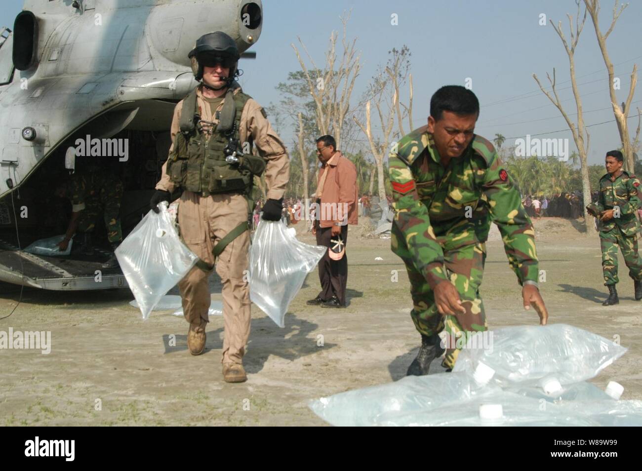 Stati Uniti Marines dal ventiduesimo Marine Expeditionary Unit (Operazioni speciali in grado) e soldati da l'esercito del Bangladesh spostare sacchi di acqua fresca da una CH-46 Sea Knight elicottero in Shoronkhola, Bangladesh, su nov. 27, 2007. L'assalto anfibio nave USS Kearsarge (LHD 3) e avviato gli elementi conduttori sono l assistenza umanitaria/i soccorsi in risposta al Bangladesh la richiesta di assistenza dopo il ciclone tropicale Sidr ha colpito la costa su nov. 15. La tempesta ha causato la morte di oltre 3 mila persone e ha lasciato centinaia di migliaia di senzatetto. Il Dipartimento della Difesa di sforzo è parte di un Foto Stock