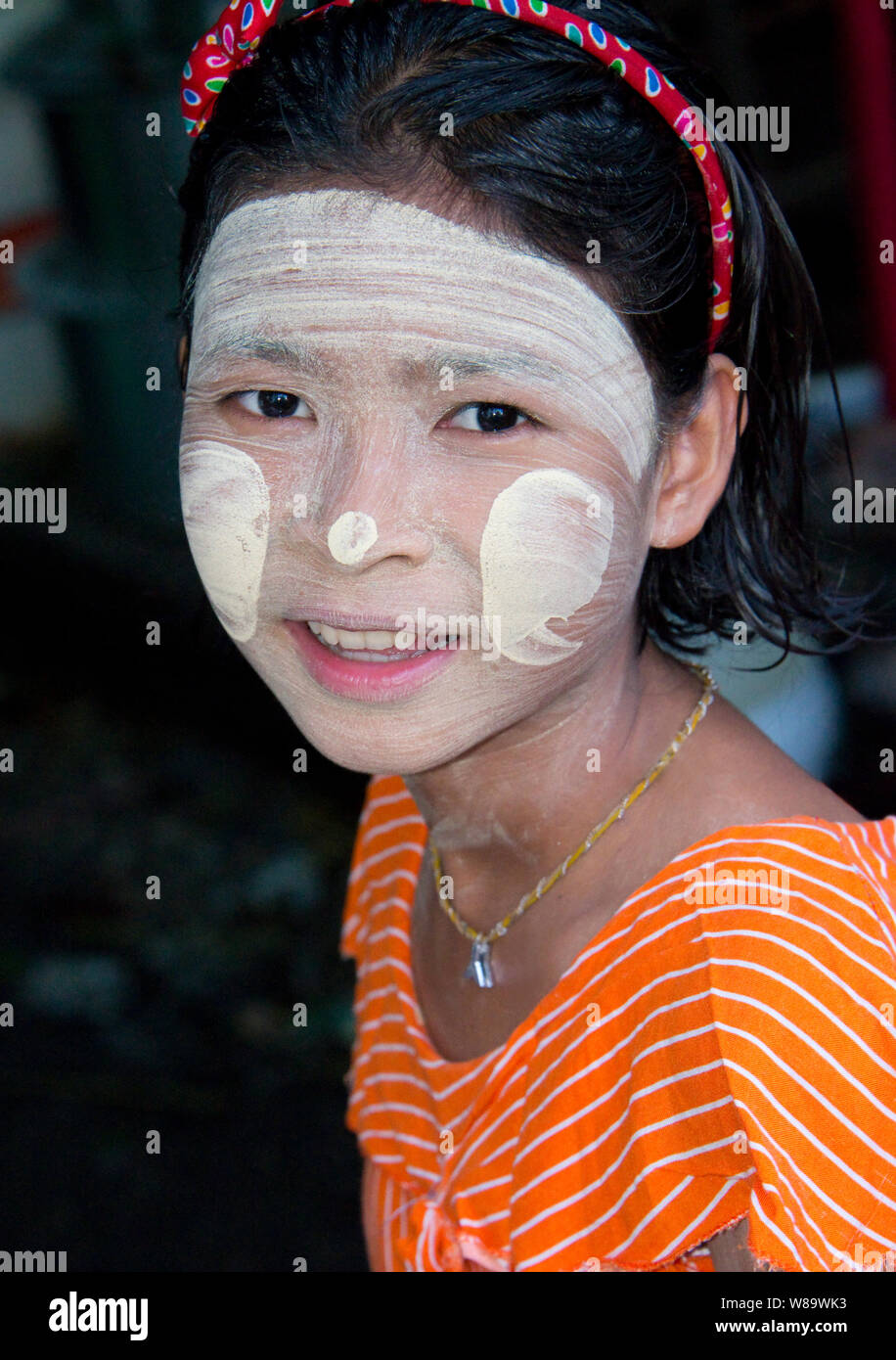 Una giovane ragazza birmano con il tradizionale Thanaka trucco sulla quale è un bianco pasta di cosmetici per la protezione solare guardando la telecamera in Bagan Myanmar Foto Stock