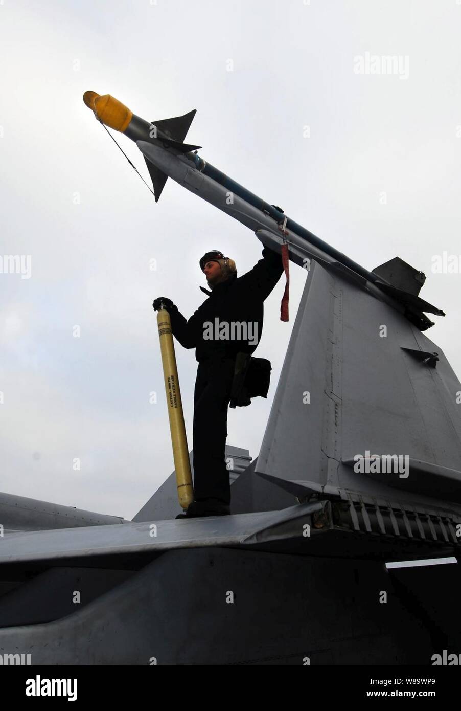 Stati Uniti Navy Aviation Ordnanceman 3rd Class Ruben Alfonso sorge su di un'ala di un F/A-18C Hornet aeromobile prima di eseguire un controllo finale su un'AIM Sidewinder air-air missile sul ponte di volo a bordo della Nimitz-class portaerei USS John C. Stennis (CVN 74) mentre è in corso nell'Oceano Pacifico il 13 giugno 2008. La Stennis e Carrier aria Wing 9 sono adattate di conduzione della nave la disponibilità di formazione al largo della costa della California del Sud. Foto Stock