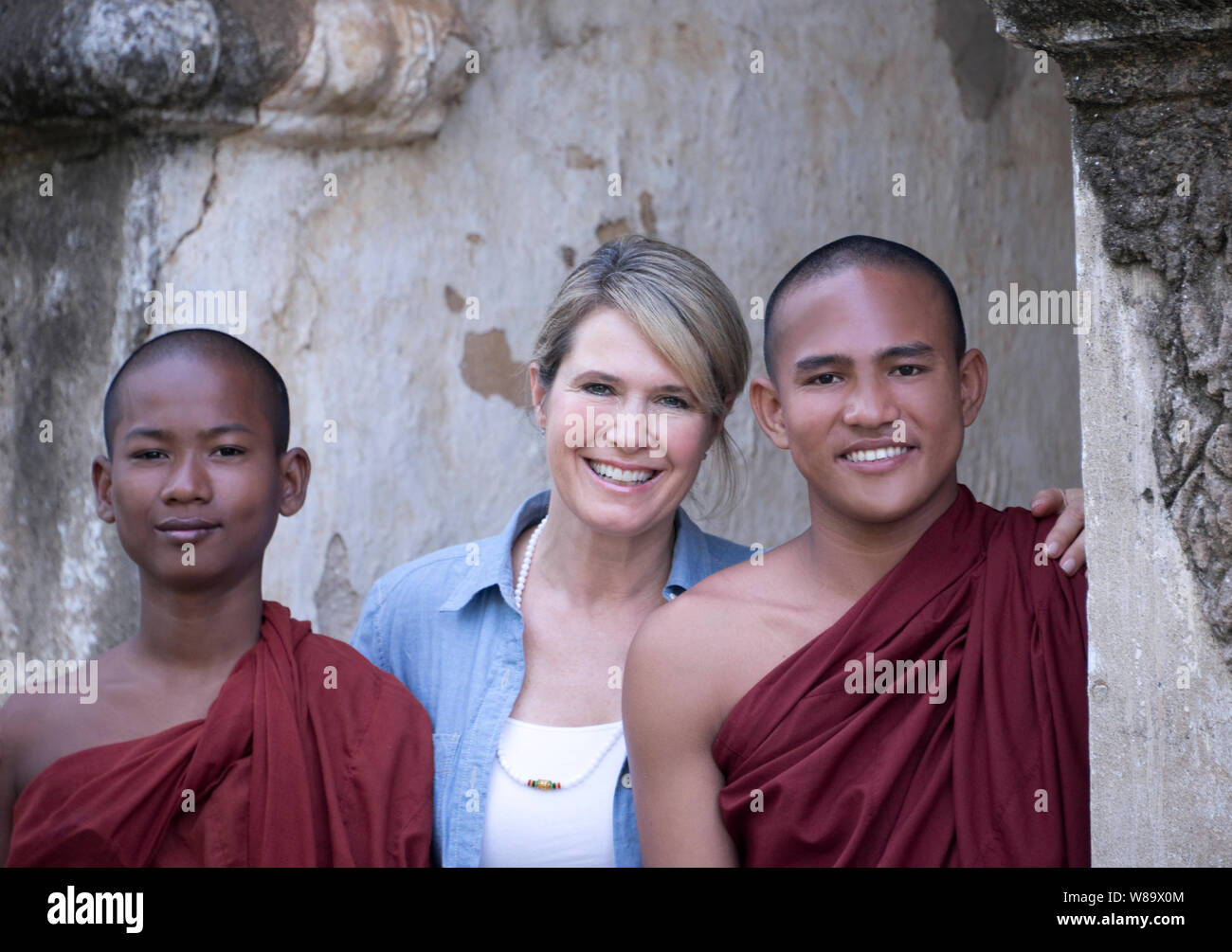 Un Felice turista femminile e due giovani birmani monaci buddisti nel Tempio Dhammayangyi a Bagan Myanmar sorridente alla telecamera la donna è rilasciato. Foto Stock