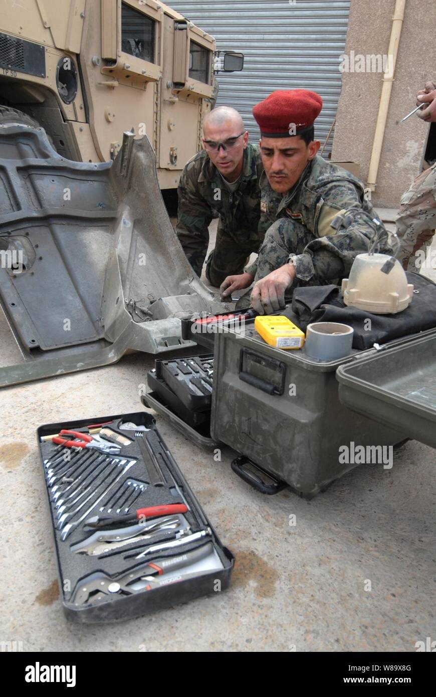 Stati Uniti Army Sgt. Raymond Averesch (sinistra) dalla transizione militare e il Team di Formazione treni un soldato iracheno con il 6° Divisione iracheno per cambiare i gruppi faro su un Humvee in Kadhimiya, Iraq, nel febbraio 23, 2009. Foto Stock