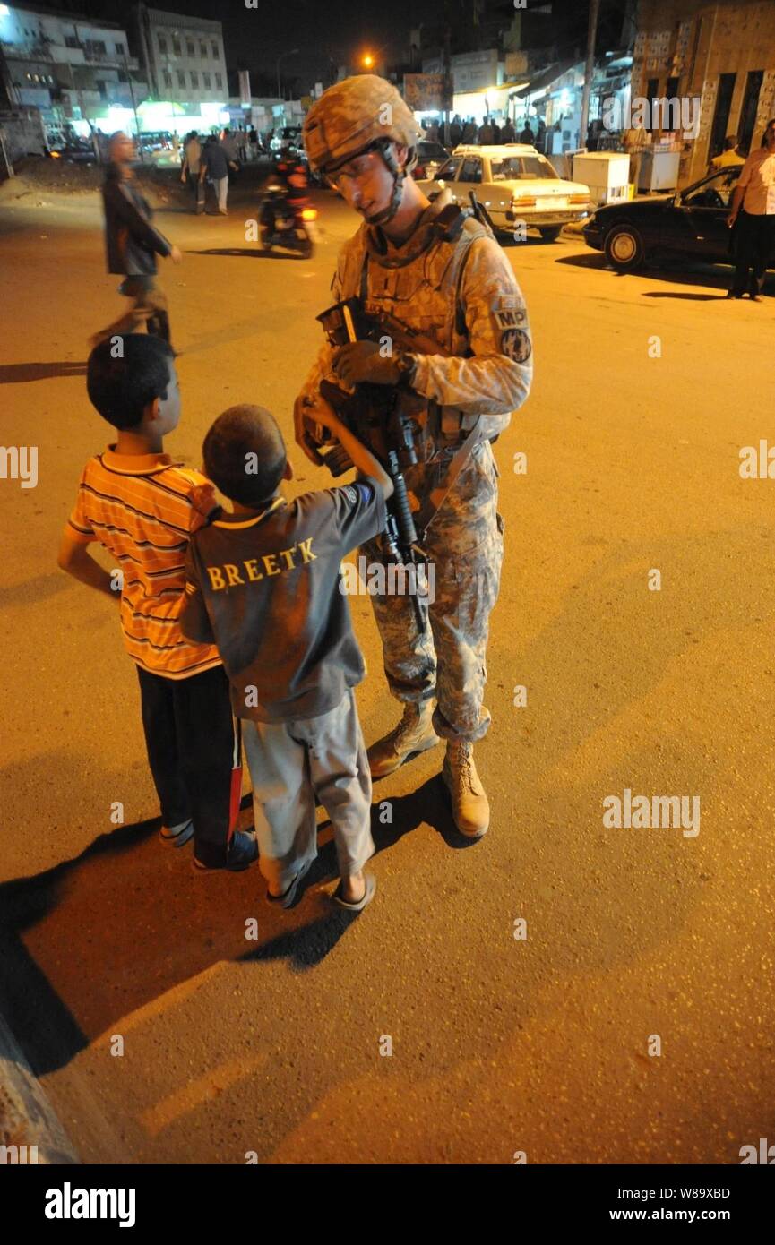 Stati Uniti Esercito 1Lt. Joshua Trulock dal 978th Polizia Militare Company, 93Battaglione, 8 Polizia Militare Brigata parla ai bambini durante un pattugliamento comune con poliziotti iracheni nell'area Kadamiyah di Baghdad, Iraq, il 27 marzo 2009. Foto Stock