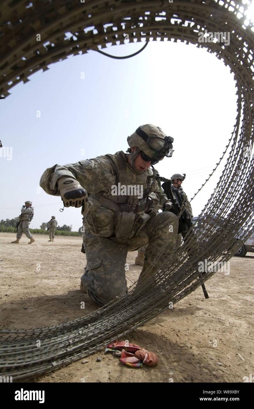 Stati Uniti Army Spc. Zachary Sexton distribuisce il filo di concertina intorno all'entrata di un ripiego clinica medica in Abu Bakr, Iraq, il 7 aprile 2009. I soldati stanno preparando la possibilità per il personale medico dal Ministero iracheno della Sanità, che fornirà assistenza medica gratuita e consultazione ai residenti di zona. Sexton viene assegnato al primo battaglione, xxiv Reggimento di Fanteria, 1° Stryker Brigade Combat Team, XXV divisione di fanteria. Foto Stock