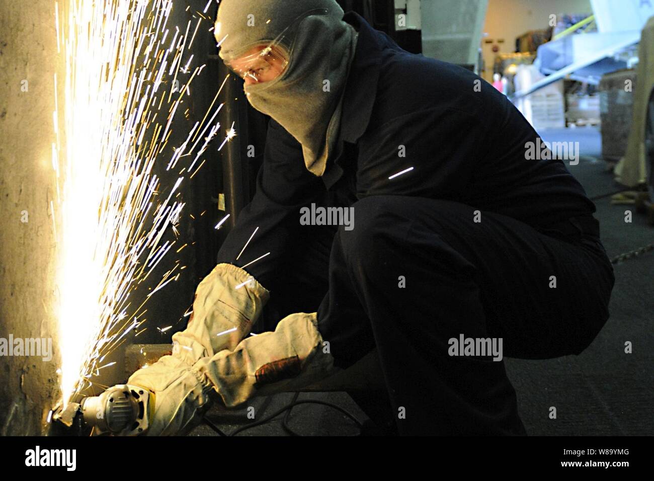 Stati Uniti Navy Seaman Anthony Fleeman grind off i pericoli per la sicurezza nell'hangar bay a bordo della portaerei USS Carl Vinson nell'Oceano Pacifico il 20 dicembre, 2010. Fleeman è uno scafo tecnico di manutenzione vigili del fuoco apprendista. Foto Stock