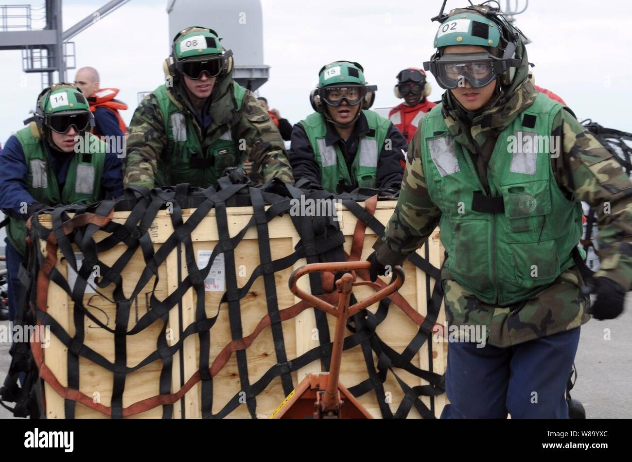 Petty Officer 2a classe Shizhen Huang (destra), assegnato all'elicottero leggero Anti-Submarine Squadron 51, tira un pallet di forniture per il ponte di volo dell'U.S. 7 Comando della Flotta nave USS Blue Ridge (LCC 19) nel Mare della Cina del Sud il 21 marzo 2011. La Blue Ridge trasferiti i pallet di assistenza umanitaria per le forniture militari comando Sealift flotta oliatore di rifornimento USNS Pecos (T-AO 197) per supportare il funzionamento Tomodachi soccorsi in Giappone. Foto Stock