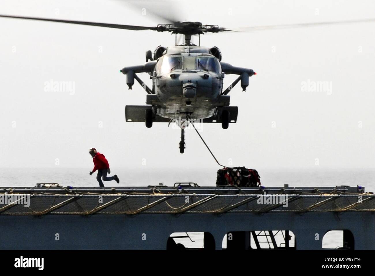 Un MH-60S Seahawk elicottero trasporta aiuti umanitari materiali di consumo dai militari di comando Sealift carichi secchi e munizioni nave USNS Matthew Perry (T-AKE 9) all'assalto anfibio nave USS Essex (LHD 2) nel Mare delle Filippine il 15 marzo 2011. L'Essex è in corso in Giappone per fornire assistenza umanitaria in quanto diretto a sostegno dell'operazione Tomodachi. Foto Stock