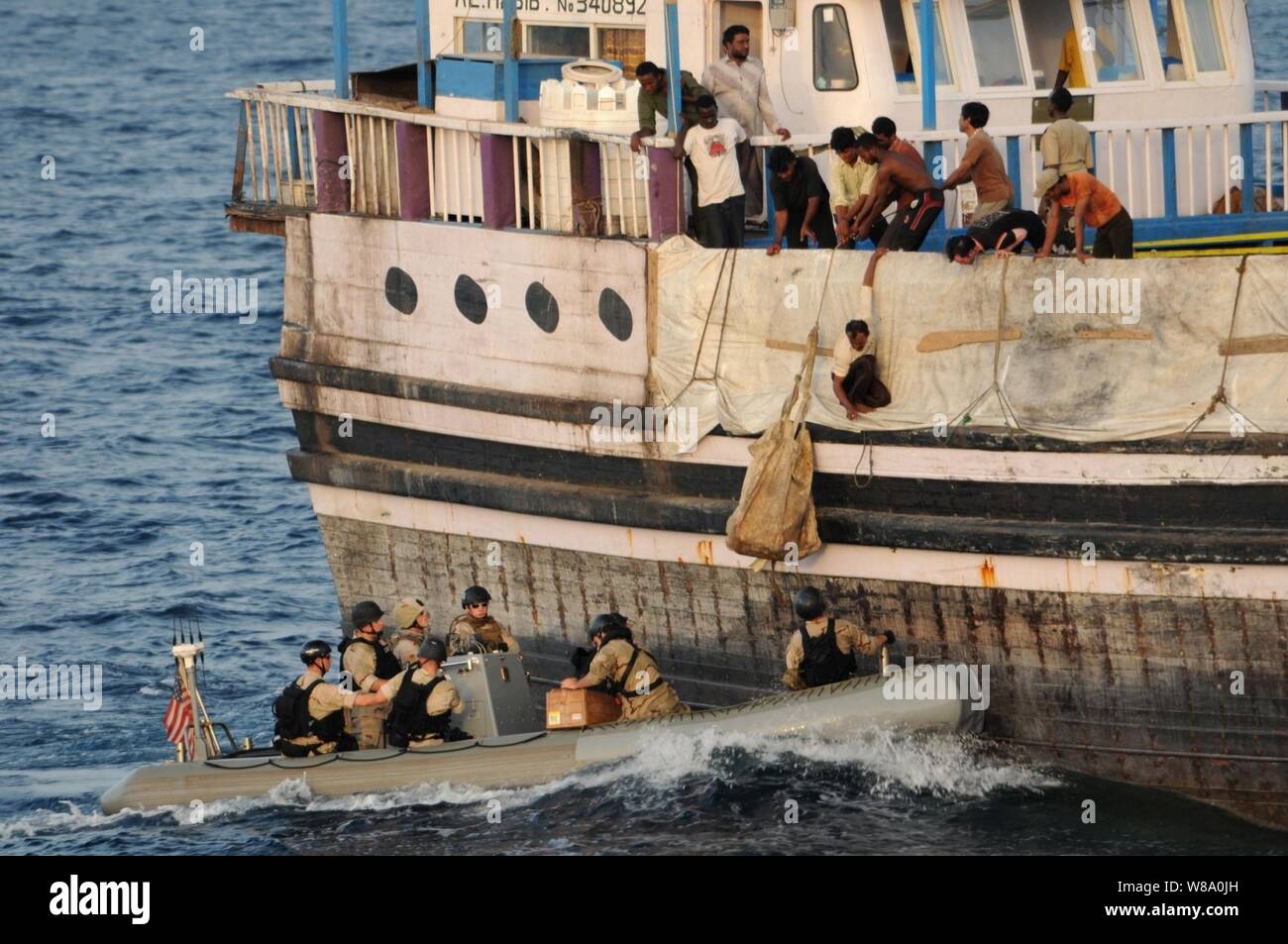 Rewmembers a bordo Al Habib, una dello Sri Lanka-contrassegnato nave da carico, paranco un sacco di forniture da una visita, scheda, ricerca e sequestro di team in uno scafo rigido barca gonfiabile nel Golfo di Aden su agosto 13, 2011. Il team della marina e una guardia costiera di interdizione avanzata team sono distribuiti dal missile destroyer USS Mitscher (DDG 57) nel Golfo di Aden. Foto Stock