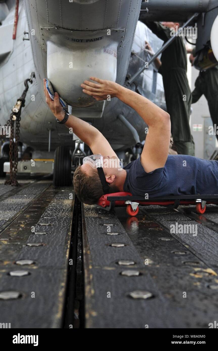 Stati Uniti Navy Petty Officer di terza classe Corey Miller, assegnato all'elicottero Anti-Submarine luce Squadron 46, lambisce la parte inferiore della sezione di coda di una SH-60B Mare Hawk elicottero sul ponte di volo dell'guidato-missili cruiser USS Anzio (CG 68) nell'Oceano Atlantico il 6 dicembre 2011. L'Anzio è un conduttore di sette mesi di distribuzione per gli Stati Uniti La quinta e la sesta flotta aree di responsabilità. Foto Stock