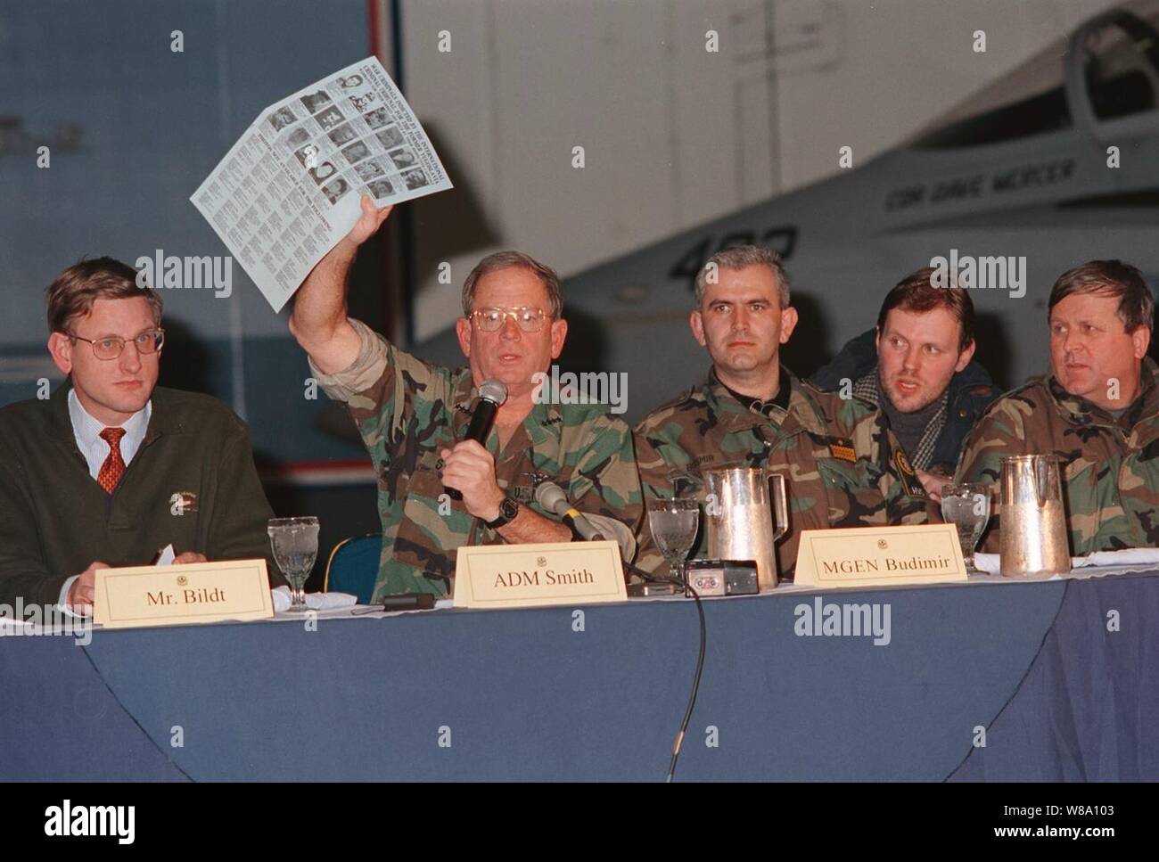 Adm. Leighton W. Smith Jr., visualizza una 'Wanted' poster durante la commissione militare congiunta conferenza stampa tenuta sul bordo dell'U.S. Nucleare NavyХs powered portaerei USS George Washington (CVN 73). Il flyer include foto, i nomi e le descrizioni dei criminali di guerra incriminati dal Tribunale Penale Internazionale per la ex Iugoslavia. Anche partecipando alla riunione erano (da sinistra a destra) Il sig. Carl Bildt, alto rappresentante, ADM. Leighton W. Smith Jr., comandante della NATO-led forze di attuazione, il Mag. Gen. Zivko Budimir, commander-in-Chief, Croato Counsel di difesa, il suo tran Foto Stock