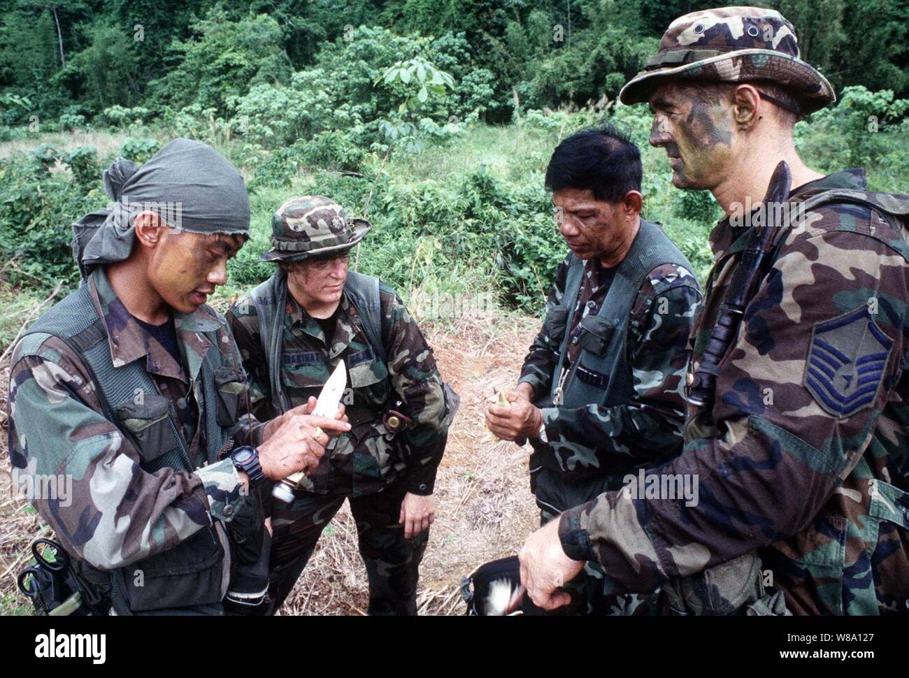 Royal Thai Air Force Sgts. Sutthiphan Jankeeree (sinistra) e Khvunchi Pinij mostrano U.S. Air Force Il Mag. Jean C. Trakinat e Master Sgt. Joe Sitterly la parte commestibile di una banana tree come parte della ricerca e salvataggio della formazione a Khao Na Ting, Thailandia, il 13 maggio 1996, durante l'esercizio Cobra Gold Ф96. Cobra Gold Ф96 è il più recente di una serie continua di Stati Uniti/Thai militare esercizi pensati per garantire la pace regionale e rafforzare la capacità del Royal Thai Forze Armate per difendere la Tailandia. Circa 9.000 USA e 10.000 personale tailandese partecipano all'esercizio. Foto Stock