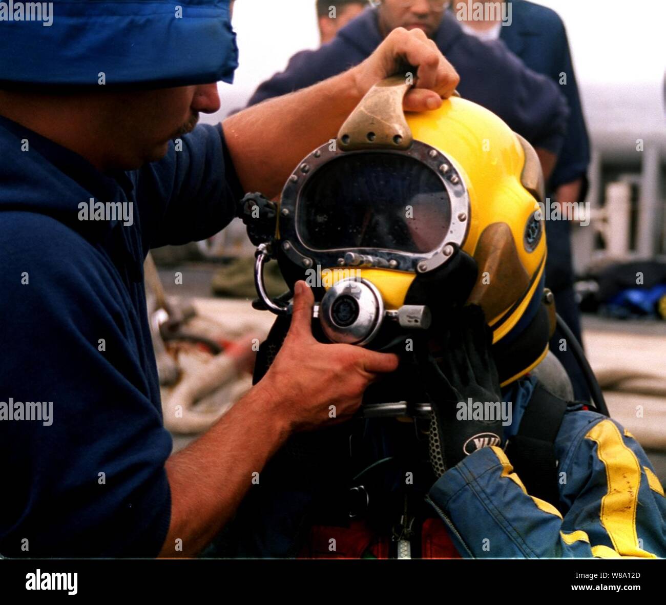 Stati Uniti Navy Diver Petty Officer 2a classe Brad Fleming è assistita con il suo marchio-21 casco immersioni in preparazione per la sua successiva immersione durante la ricerca e operazioni di recupero al volo TWA 800 crash site offshore del Moriches ingresso, Long Island, N.Y., il 25 luglio 1996. Fleming, a Palatka, Fla. native è una marina Hull tecnico. Foto Stock