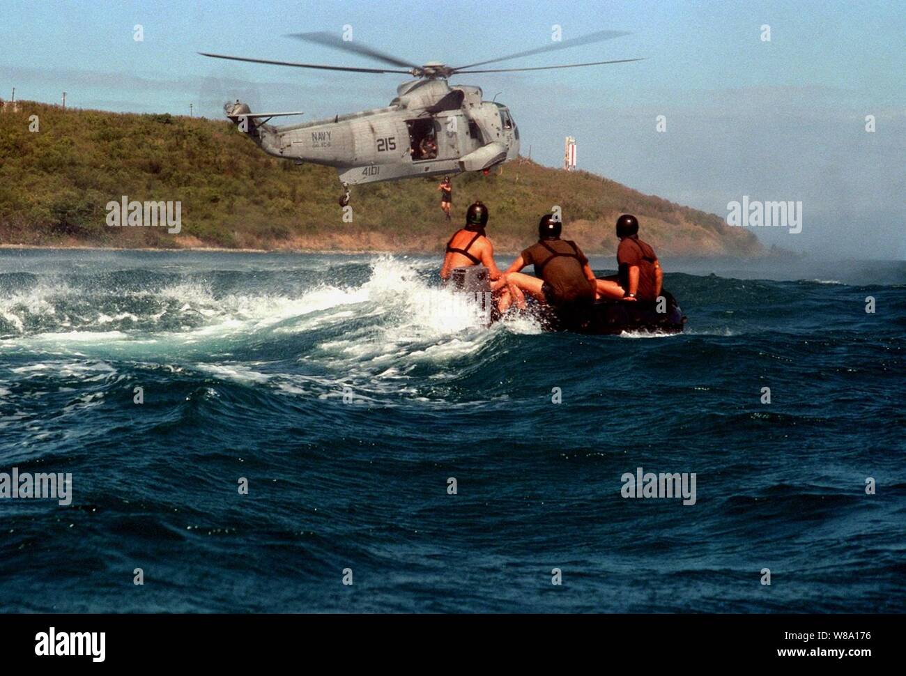 Un'eliminazione degli ordigni esplosivi tecnico salta da un U.S. Navy SH-3H Sea King elicottero in acqua come i suoi compagni di squadra guardare da una gomma di combattimento razzia craft il 17 marzo 1997. I membri del team di l'eliminazione degli ordigni esplosivi Mobil unità 2 e gli equipaggi in elicottero dalla flotta squadrone composito 8 sono la pratica di inserimento e operazioni di recupero al largo della costa della stazione navale Roosevelt strade, Puerto Rico. Foto Stock