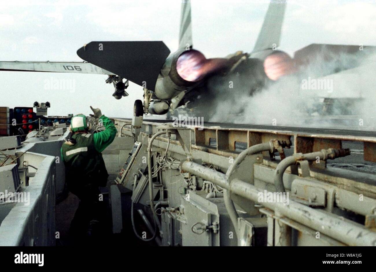Petty Officer di terza classe Giosuè segnali Schwandt un chiaro dopo il lancio di un F-14 Tomcat ruggisce sopra la sua testa dal lato della porta di catapulta della USS Indipendenza (CV 62) come la nave opera nel Golfo Persico il 22 febbraio, 1998. Indipendenza e la sua avviato Carrier aria Wing 5 sono in stazione nel Golfo Persico a sostegno del funzionamento orologio meridionale che sono gli Stati Uniti e le forze della coalizione esecuzione della no-fly zone su Iraq meridionale. Schwandt, da Sacramento, in California, è una marina aviation boatswainХs mate lancio e attrezzature di recupero operatore. Foto Stock
