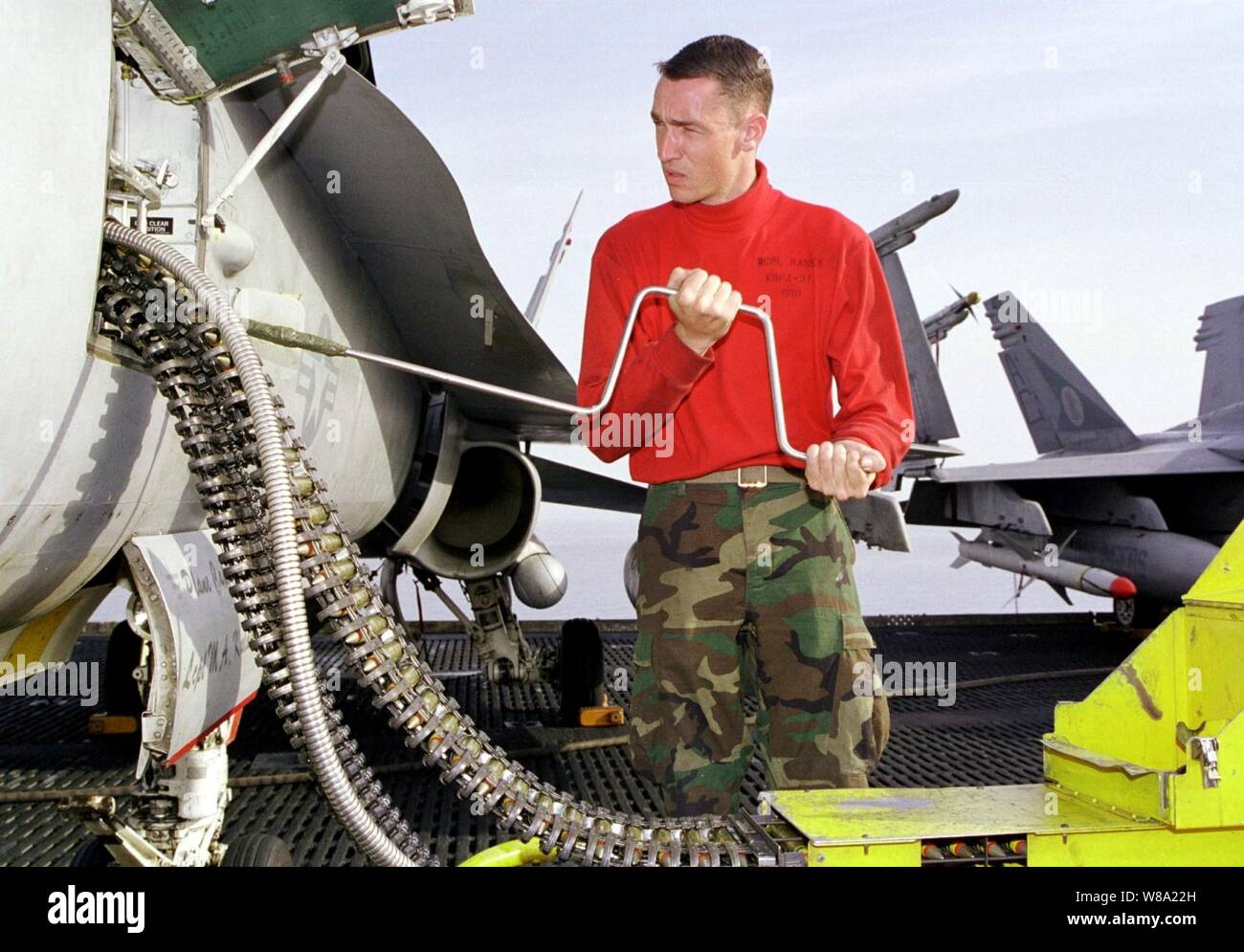 Cpl. Stephen Ramsey, U.S. Marine Corps, carichi 20 mm mitragliatrice tornate in un'F/A-18C Hornet sul ponte di volo della USS Enterprise (CVN 65) il 5 aprile 1999. Enterprise e la sua avviato Carrier aria Wing 3 sono in stazione nel Golfo Persico a sostegno del funzionamento orologio meridionale, che sono gli Stati Uniti e le forze della coalizione esecuzione della no-fly zone su Iraq meridionale. Ramsey è attaccato alle Marine Fighter Squadron di attacco 312. Foto Stock