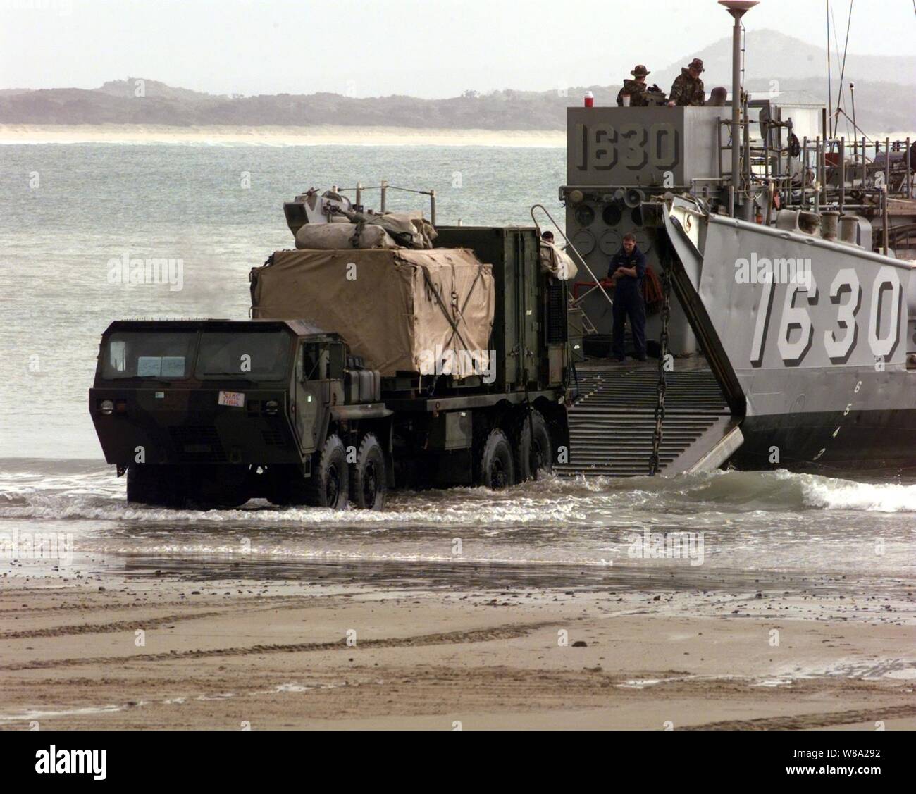 Un U.S. Marine Corps logistica veicolo trascina verso il basso la rampa della U.S. Navy Landing Craft Utility nella surf a Freshwater Beach, Australia, durante l assalto anfibio le operazioni di sbarco di esercizio Crocodile '99 al 1 ottobre, 1999. Esercizio Crocodile '99 è una combinazione di Stati Uniti e Australia formazione militare esercizio condotti presso la Shoalwater Bay Area Formazione nel Queensland, in Australia. Foto Stock