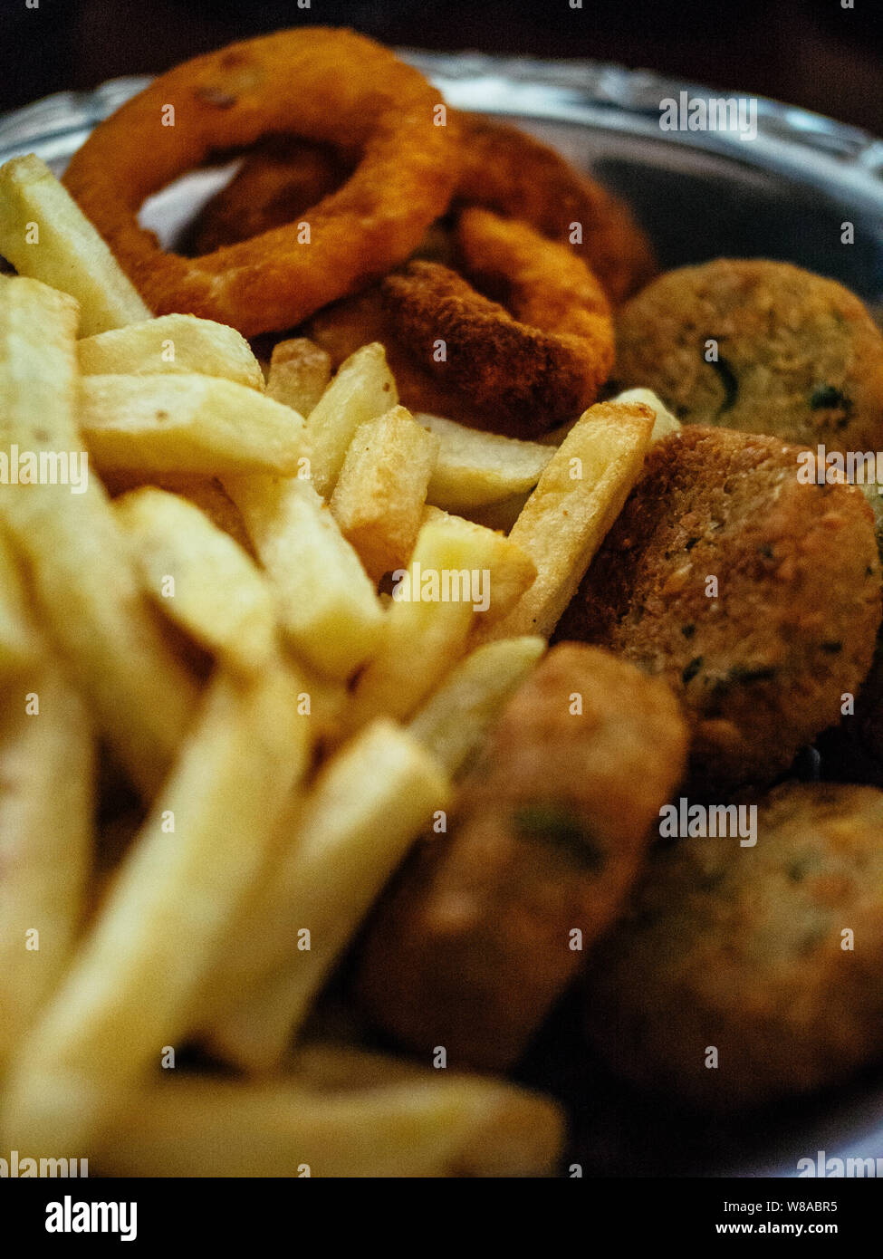 Junkfood vegana piatto con patatine fritte, falafels e anelli di cipolla Foto Stock