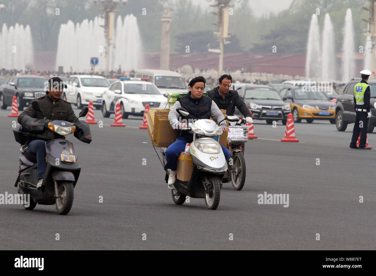 --FILE--cinese ciclisti corsa biciclette elettriche attraverso la piazza Tiananmen a Pechino, in Cina, il 6 aprile 2016. Il crescente numero di auto private drivers Foto Stock