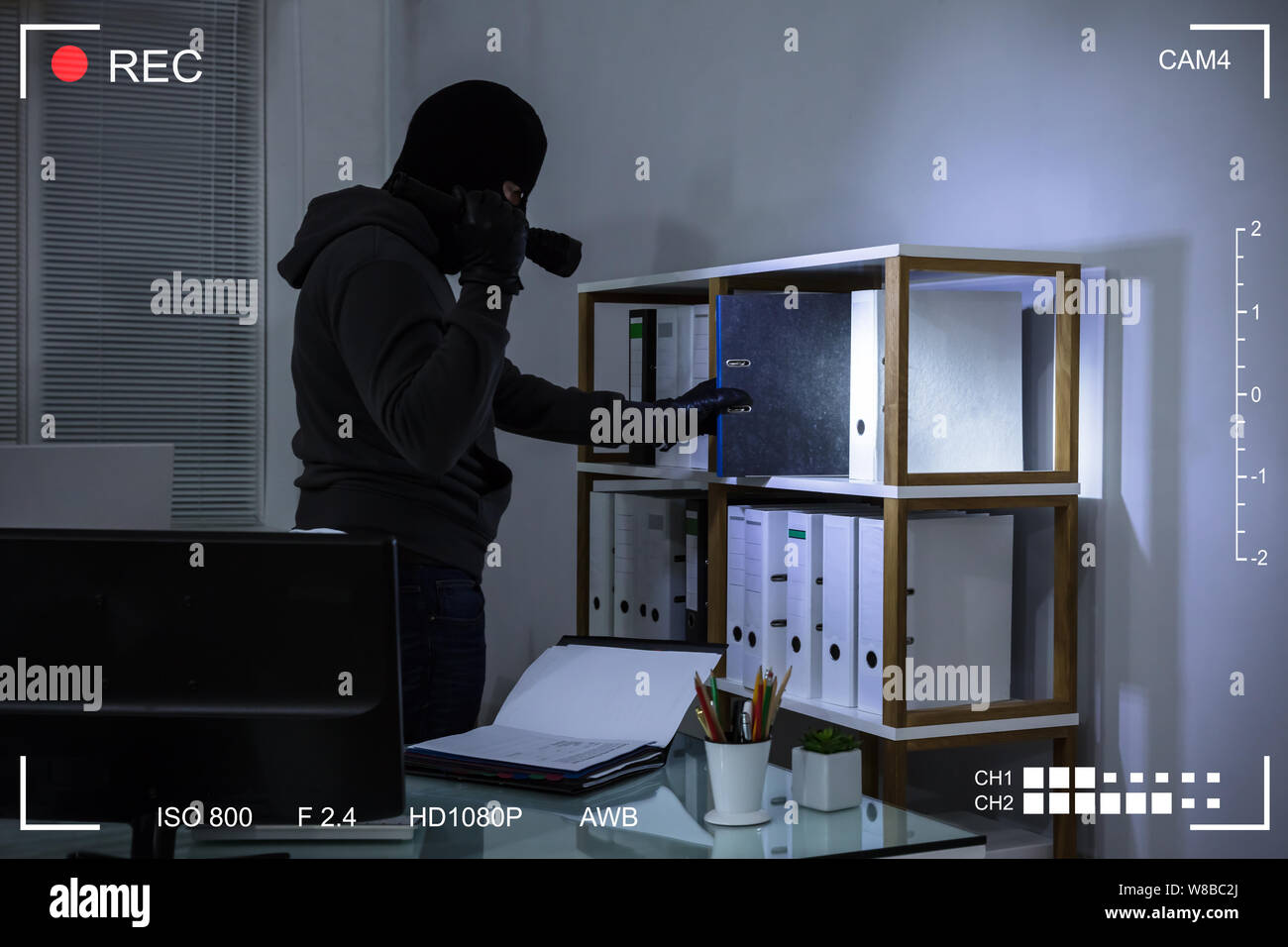 Ladro indossando passamontagna rubare file da scaffale in scena sul luogo di lavoro attraverso la telecamera TVCC Foto Stock