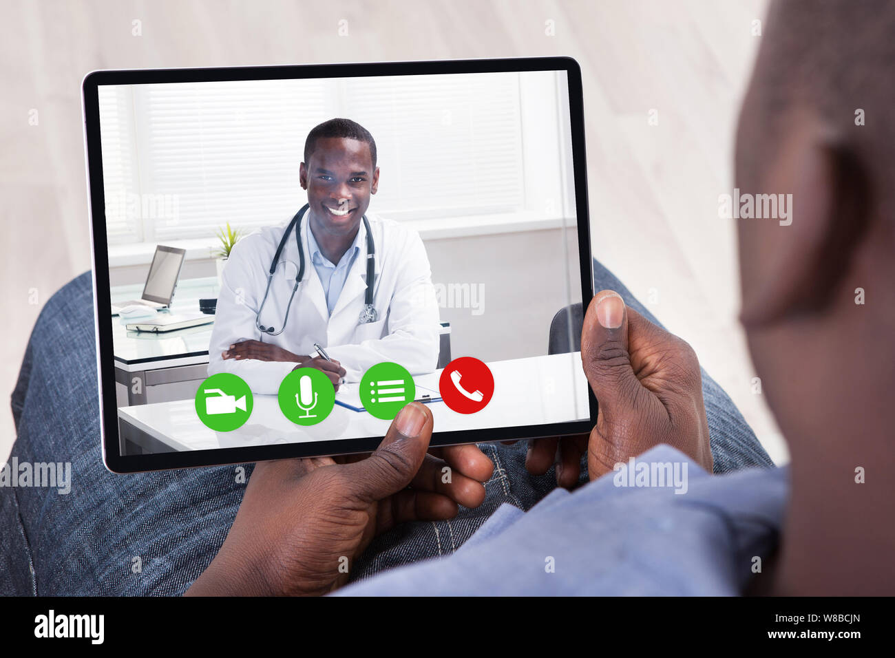 Un uomo africano fare video conferenza con il medico su tavoletta digitale Foto Stock