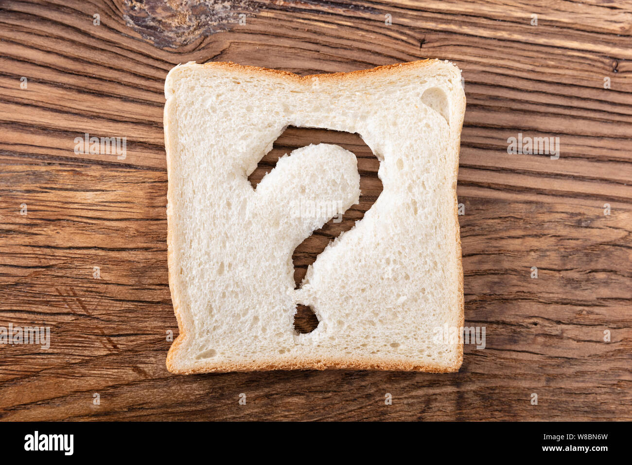 Fetta di pane con un punto interrogativo segno sulla scrivania in legno Foto Stock