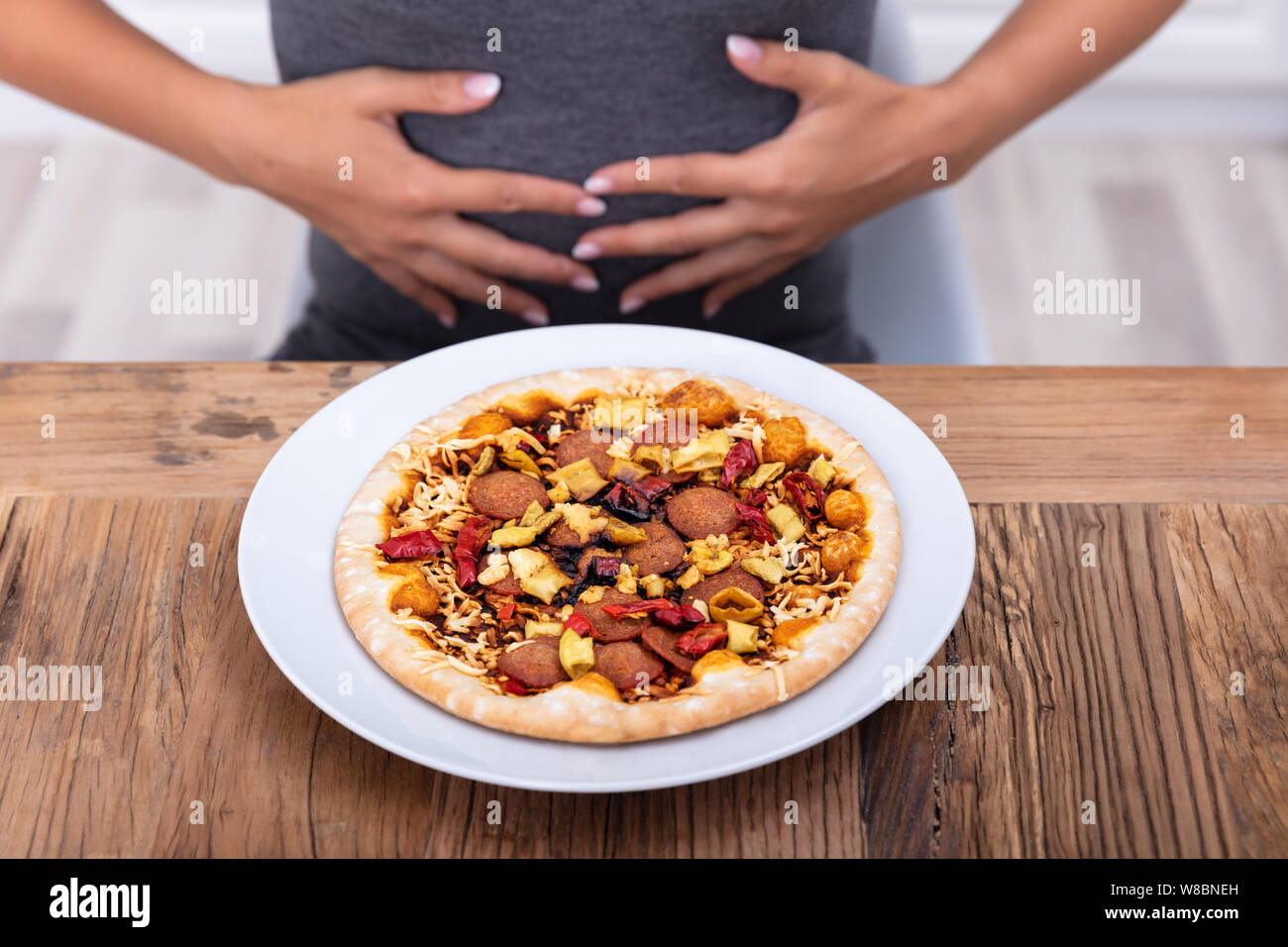 Giovane donna che soffre di dolori di stomaco mentre avente la pizza Foto Stock