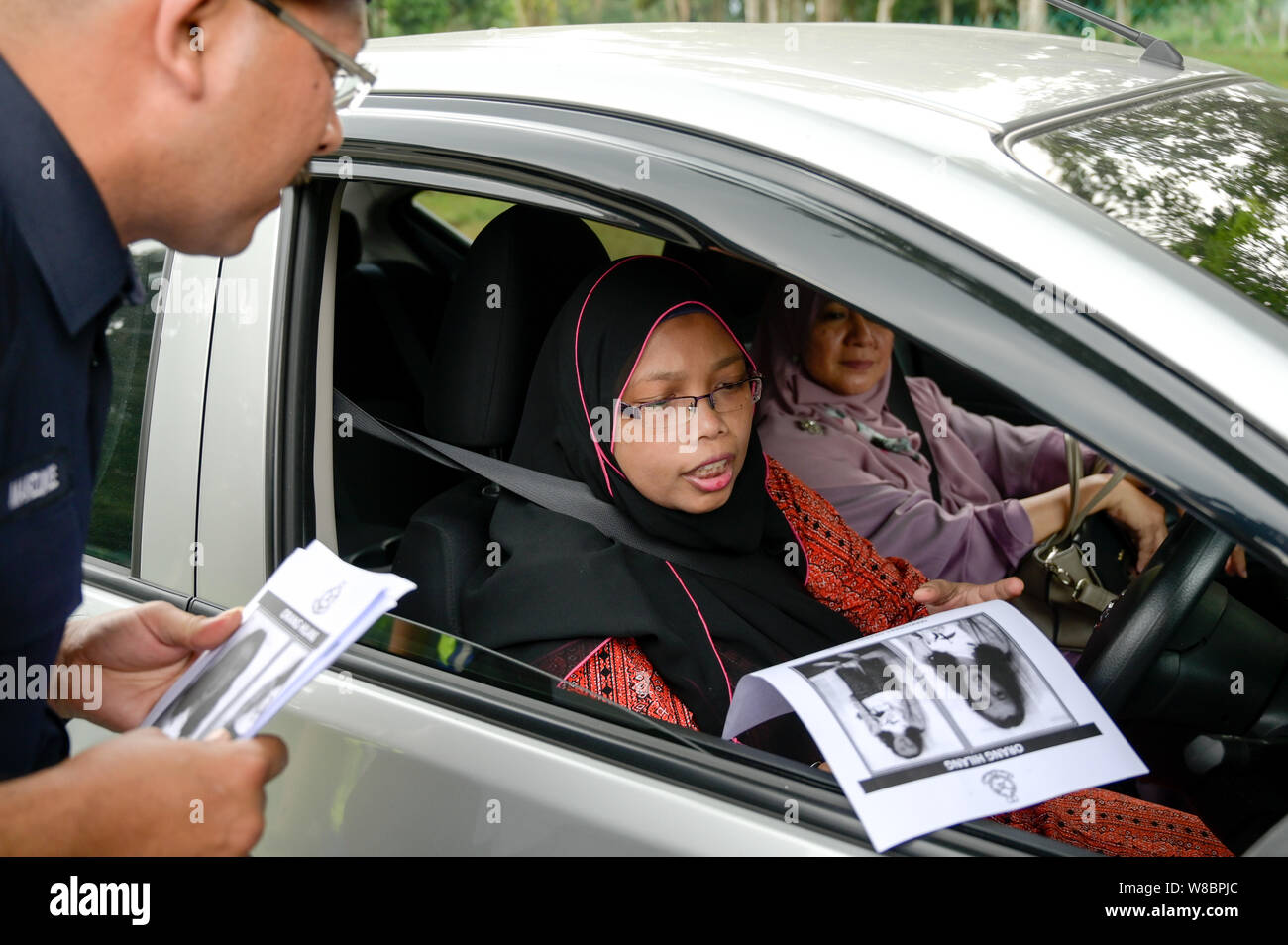 Kuala Lumpur, Malesia. Il 9 agosto, 2019. Un reale malese funzionario di polizia mani un poster per un cuscinetto di driver un ritratto della ragazza mancanti Nora Quoirin, 15, a Seremban, Negeri Sembilan, Malaysia il 9 agosto 2019. Nora è scomparso durante una vacanza con la sua famiglia al Dusun resort situato in una riserva naturale vicino a Seremban, circa 80 km a sud di Kuala Lumpur, Malesia. Nora è stata assente nella sua camera da letto il 04 agosto 2019. Credito: Chris Jung/ZUMA filo/Alamy Live News Foto Stock