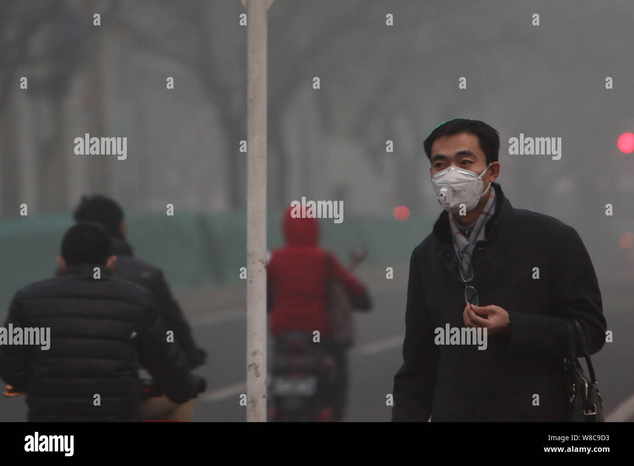 Un pedone che indossa una maschera facciale passeggiate su una strada di smog pesante a Pechino, in Cina, il 22 dicembre 2015. Inquinamento atmosferico a Pechino ha aggravato anche come ambi Foto Stock