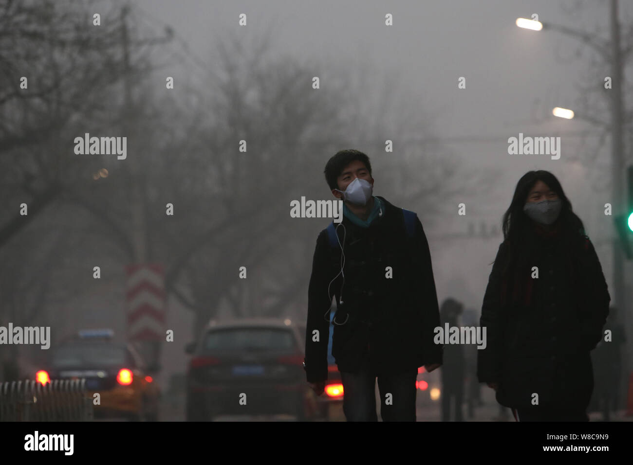 I giovani studenti di indossare maschere viso a piedi su una strada di smog pesante a Pechino, in Cina, il 22 dicembre 2015. Inquinamento atmosferico a Pechino ha aggravato anche come ambi Foto Stock