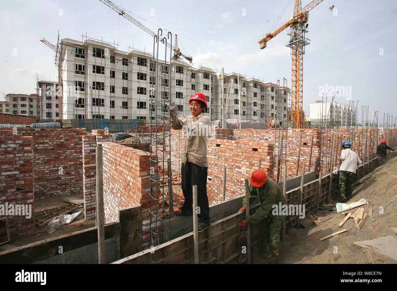 --FILE--lavoratori cinesi costruire edifici residenziali di un governo-finanziato il progetto di alloggiamento nella città Tiemenguan, a nord-ovest della Cina di Xinjiang Uygur Au Foto Stock