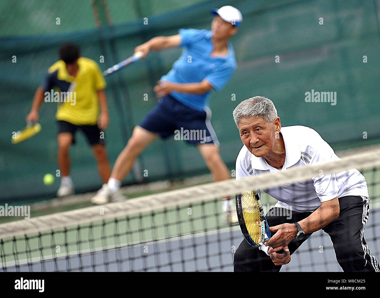 --FILE--Zhang Renpeng, un 81-anno-vecchio appassionato di sport, anteriore, si prepara a tornare un colpo durante una classe di tennis a Wuhan Istituto di Educazione Fisica Foto Stock