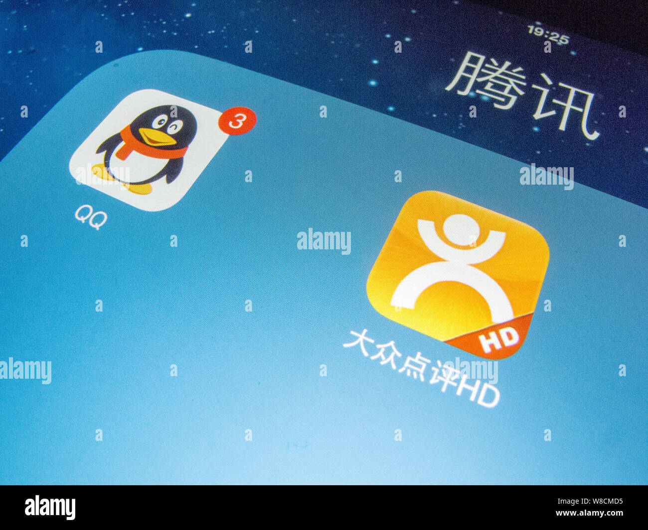 --FILE--un cinese telefono cellulare utente guarda le icone della messaggistica mobile app QQ di Tencent e il cibo e gli intrattenimenti di rating Dianping app sul suo sma Foto Stock