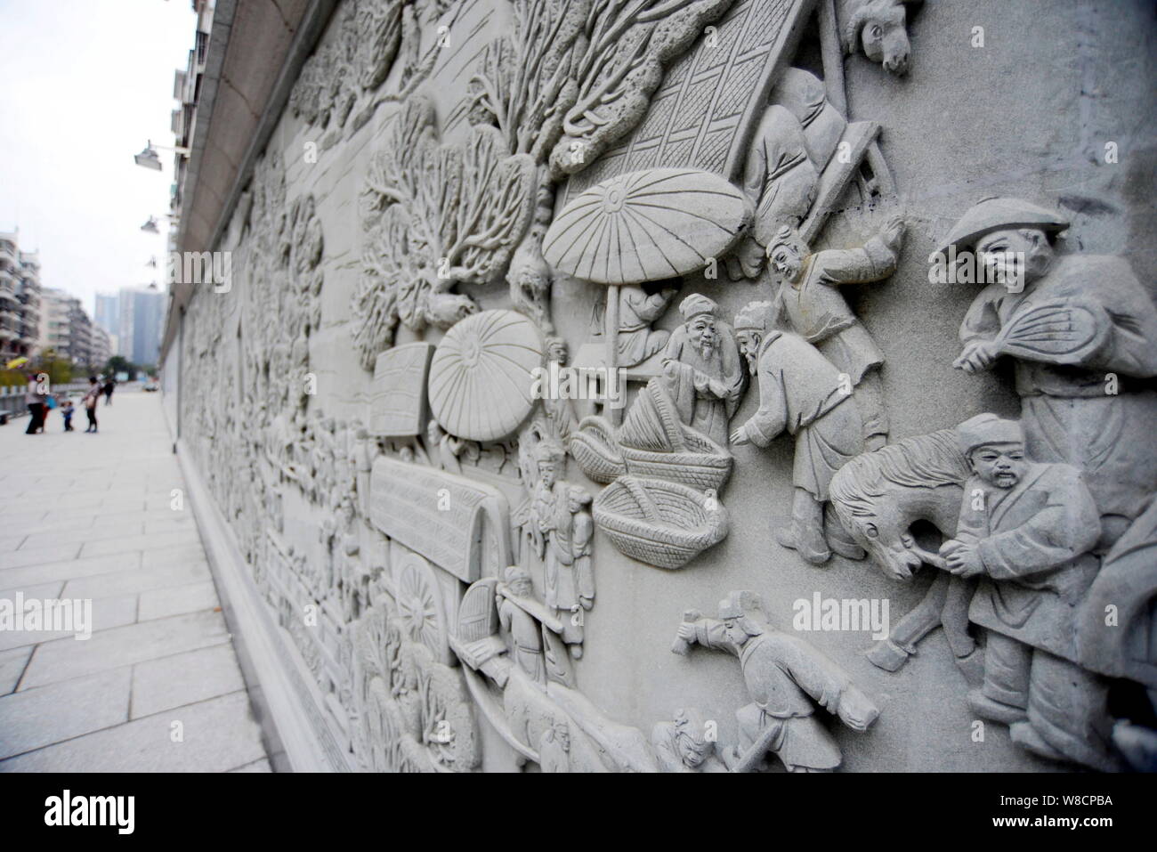 I residenti locali a piedi passato la 100 di metri lungo scultura in pietra di antica Cinese Pittura 'lungo il fiume durante il Festival Qingming' nella città di Chenzhou Foto Stock