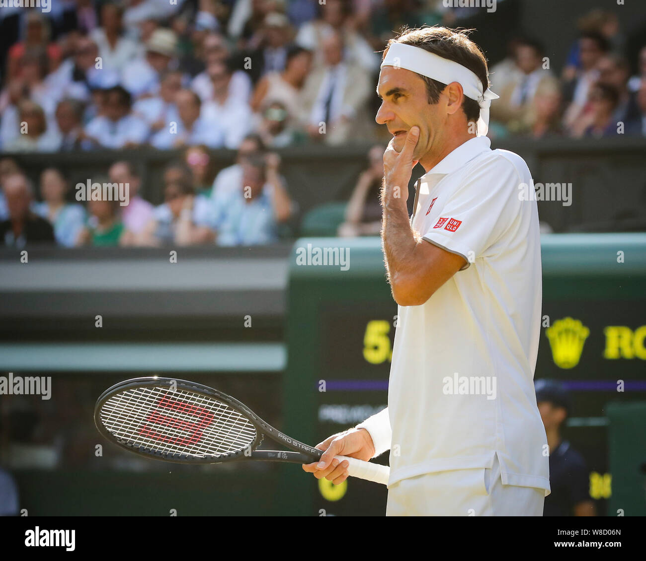 Vista laterale di pensosa Swiss giocatore di tennis Roger Federer in piedi in corte durante la partita nel 2019 campionati di Wimbledon, London, England, Regno Foto Stock